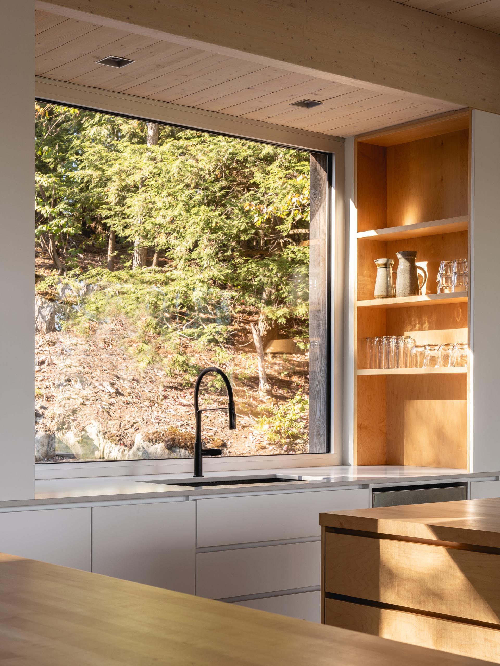 In this modern kitchen, there's two kitchen islands made from solid maple, polished concrete floors, and a large square window above the sink.