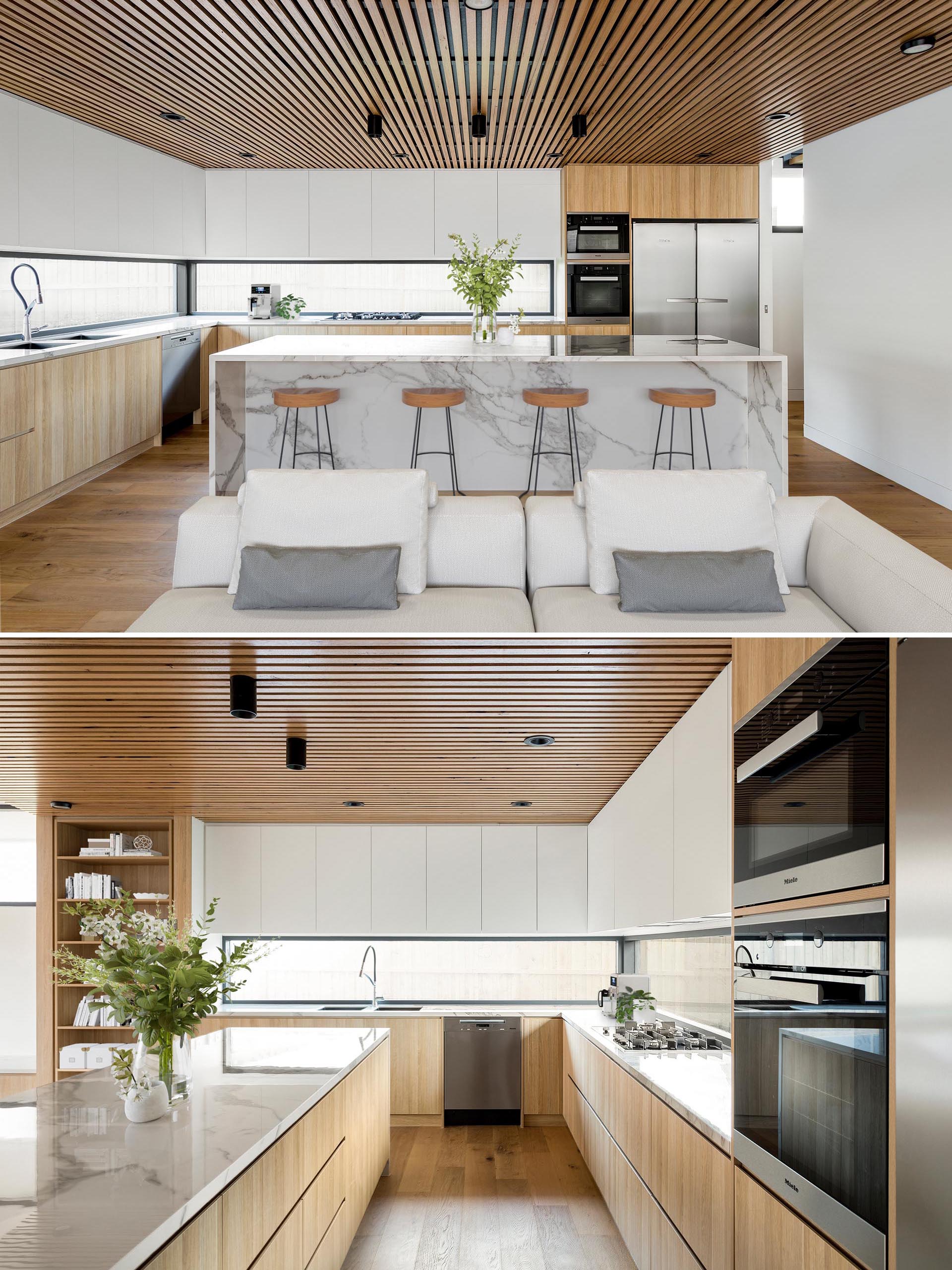Nhà bếp hiện đại với trần gỗ, tủ tối giản và đảo đá cẩm thạch.