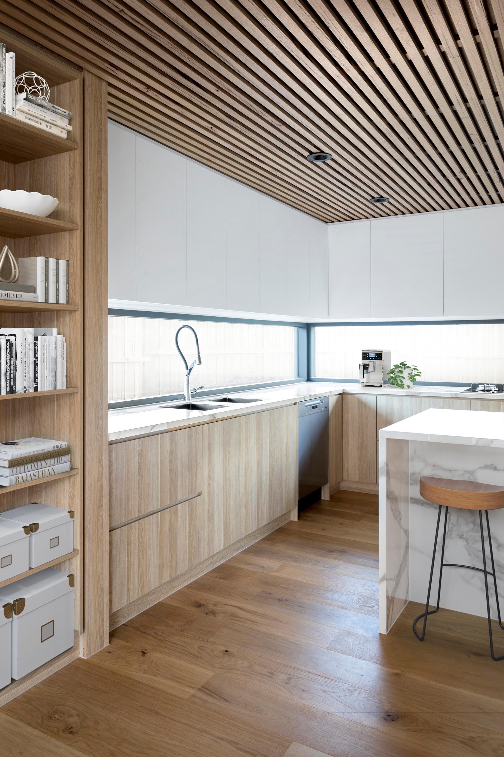 Nhà bếp hiện đại với trần gỗ, tủ tối giản và đảo đá cẩm thạch.