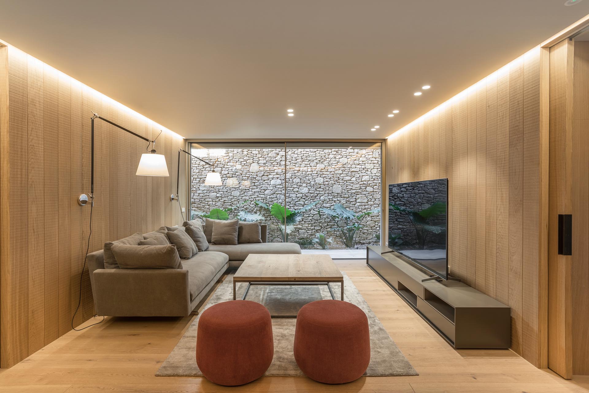 A basement living room with wood walls and floor, and hidden lighting.