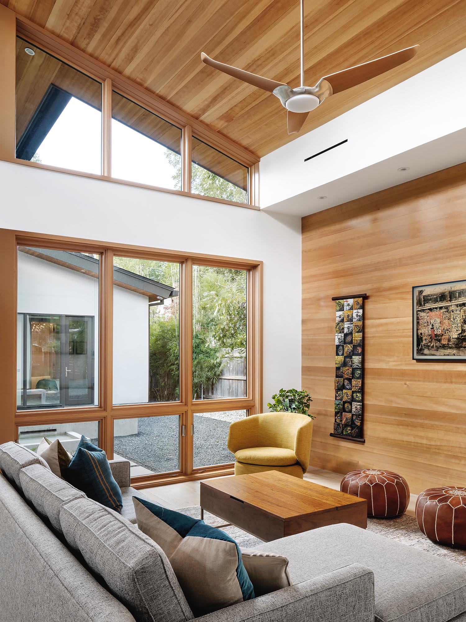 In this modern living room, a high sloped ceiling creates a lofty and open environment, while the wood adds a sense of warmth to the space.