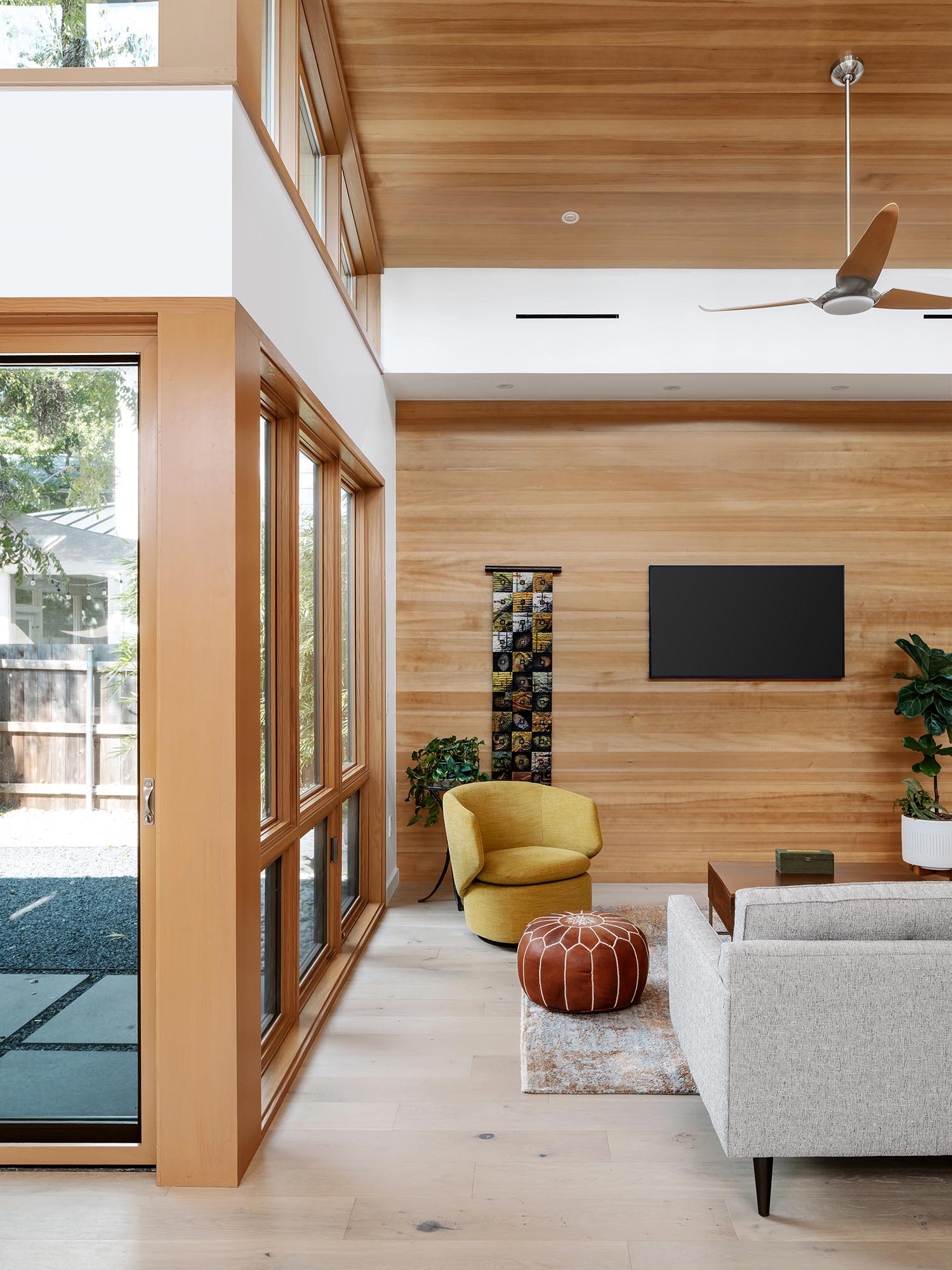 In this modern living room, a high sloped ceiling creates a lofty and open environment, while the wood adds a sense of warmth to the space.