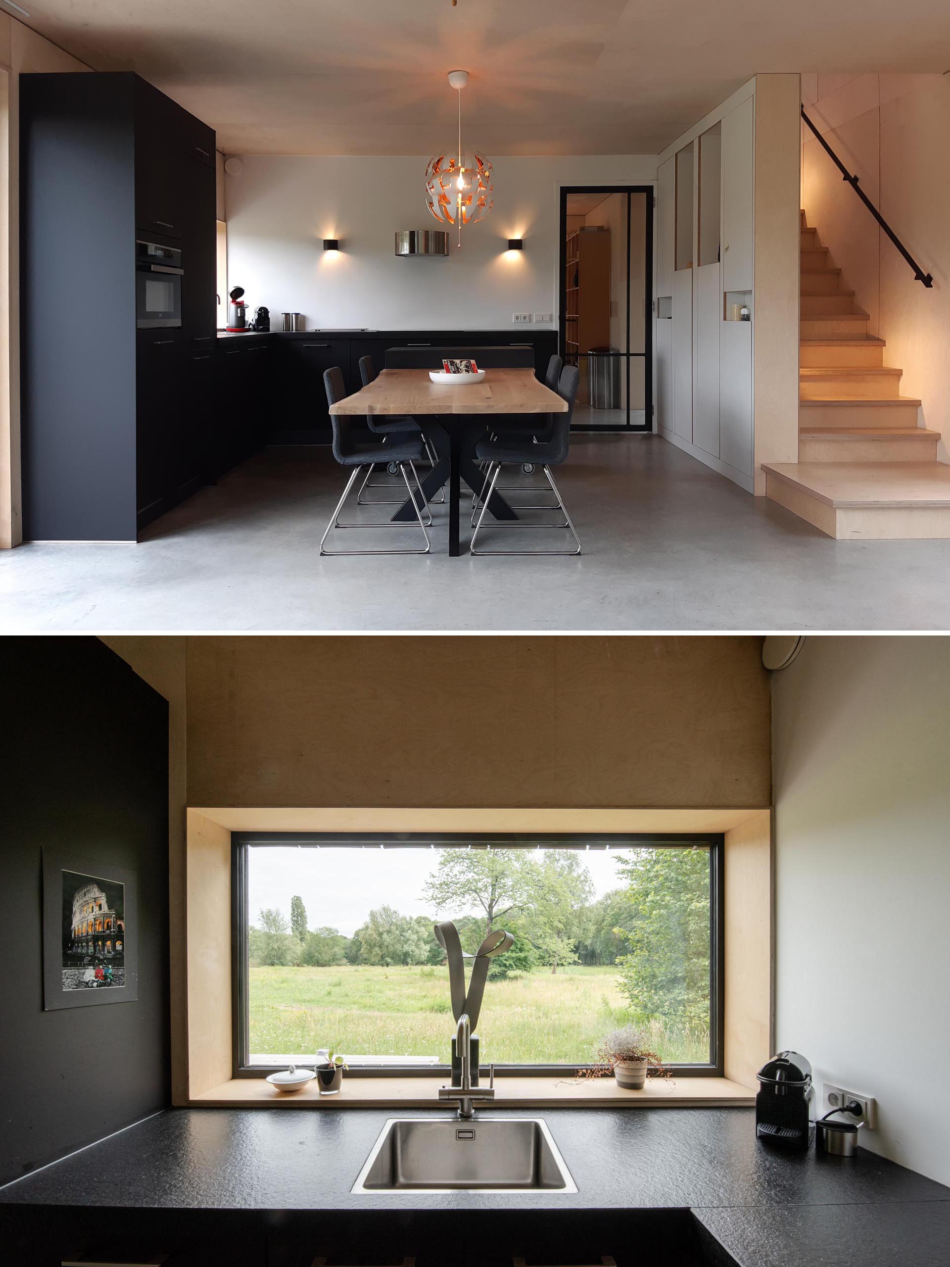 A modern matte black kitchen with wood dining table.