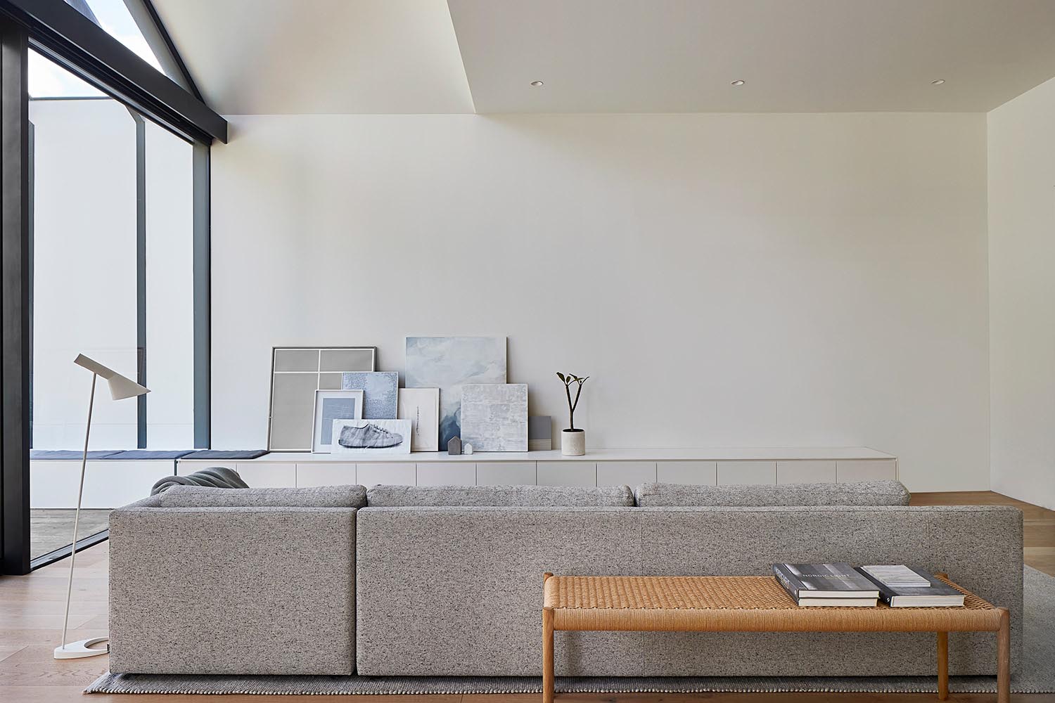 A modern living room with a neutral color palette and a low cabinet that becomes a bench outside.