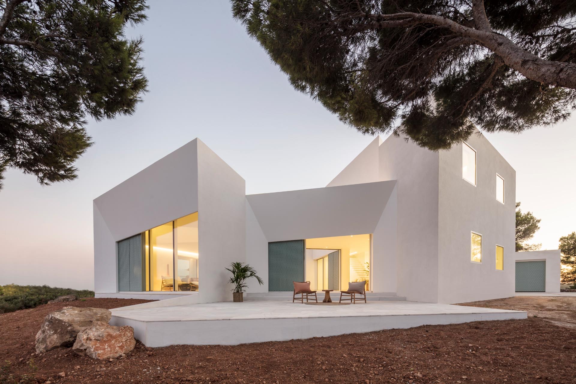 A modern white home with pastel turquoise perforated aluminum screens and an angular design.