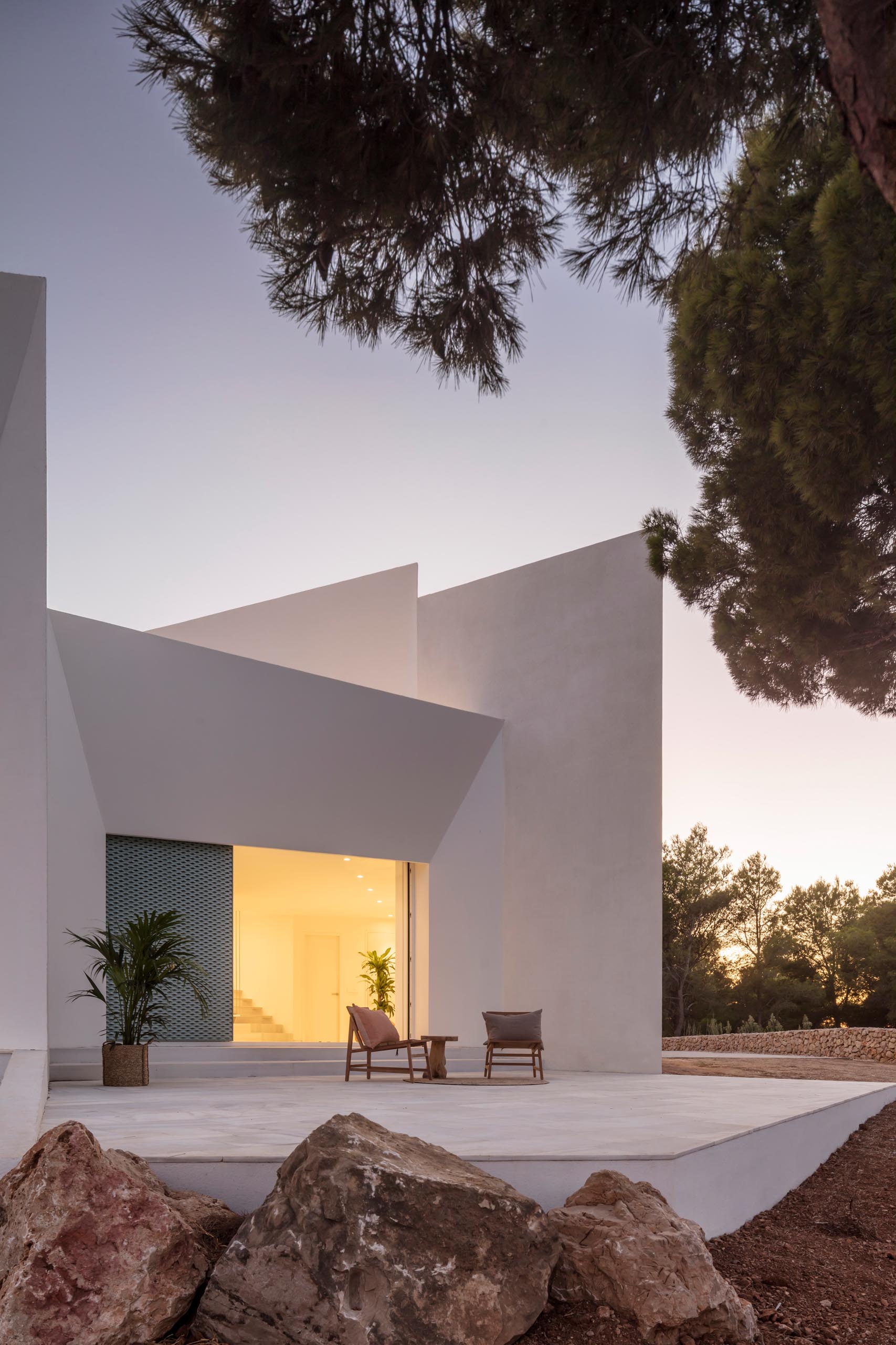 A modern white home with pastel turquoise perforated aluminum screens and multiple patios.