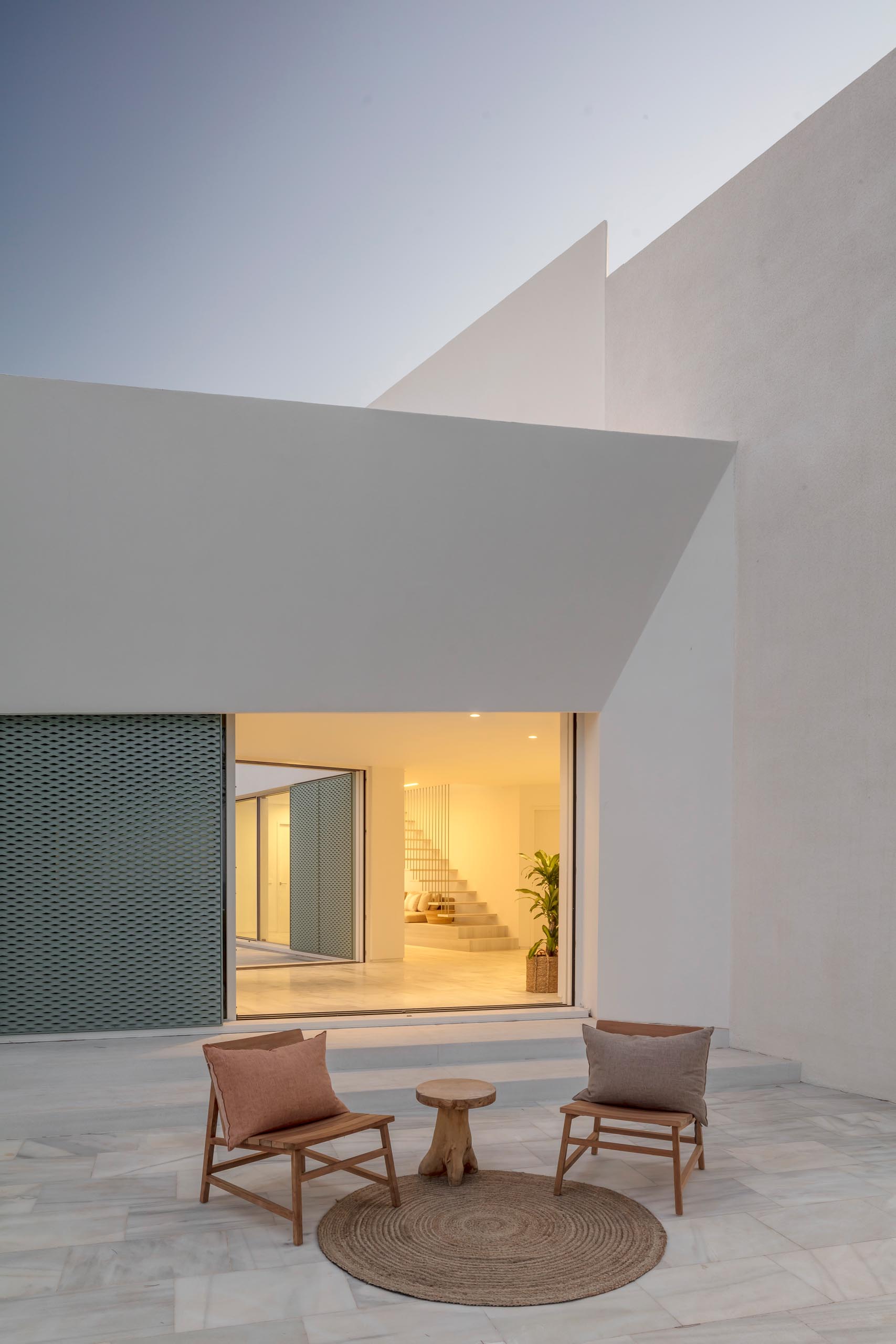 A modern white home with pastel turquoise perforated aluminum screens.