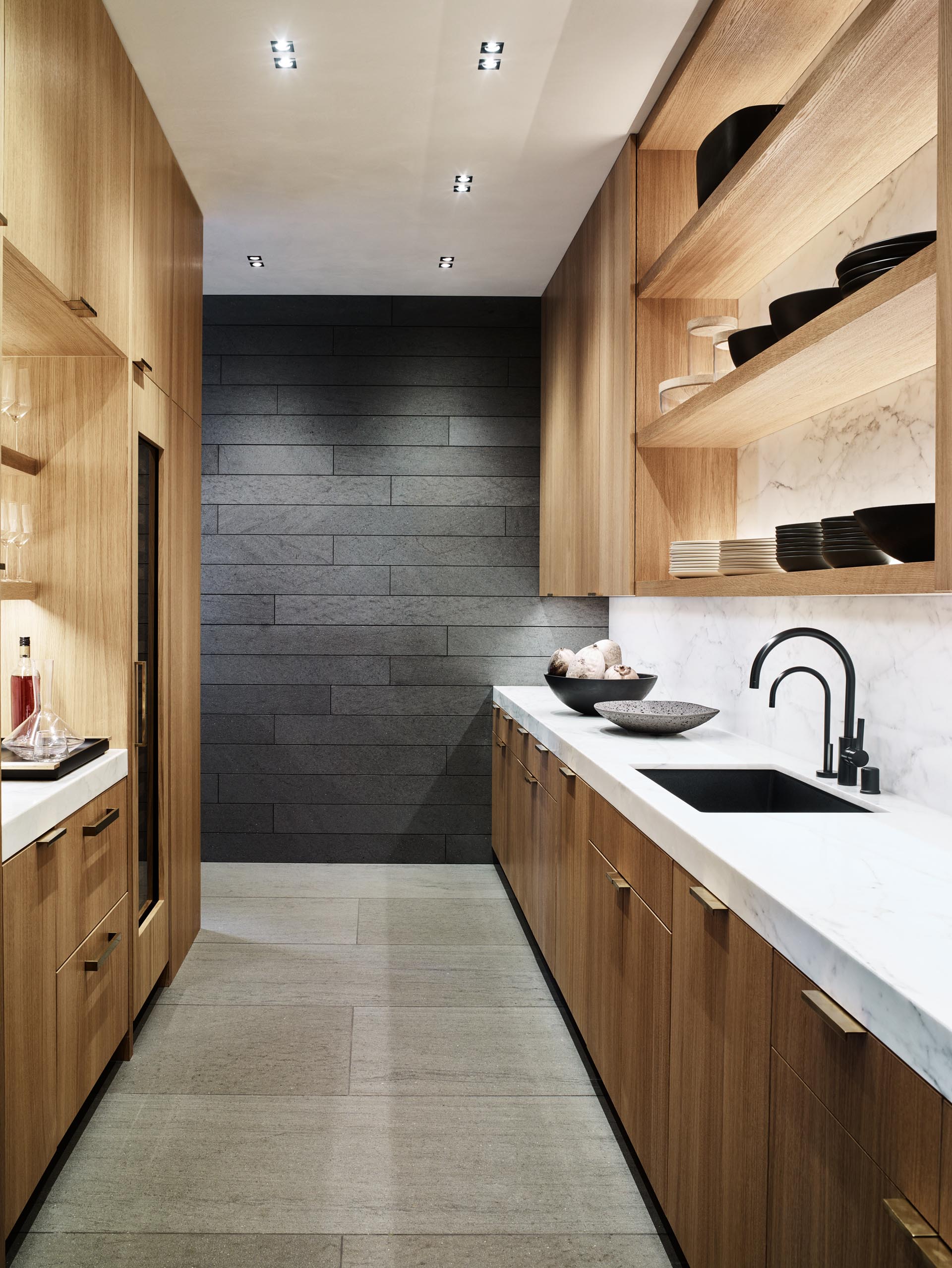 A walk-through pantry with wood cabinets and open shelving.