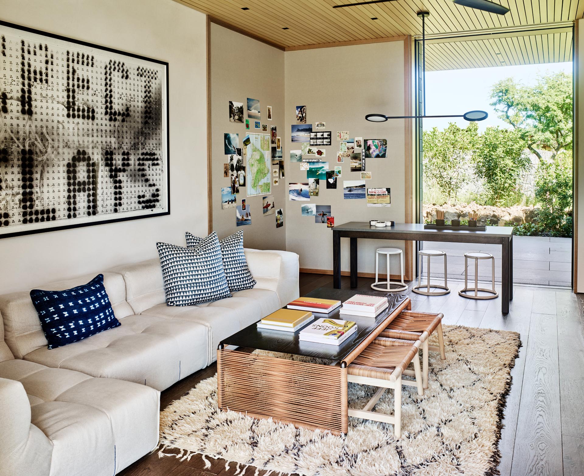 This modern playroom has been furnished with a comfortable light colored sofa, an art wall, and a table for crafting or playing games.