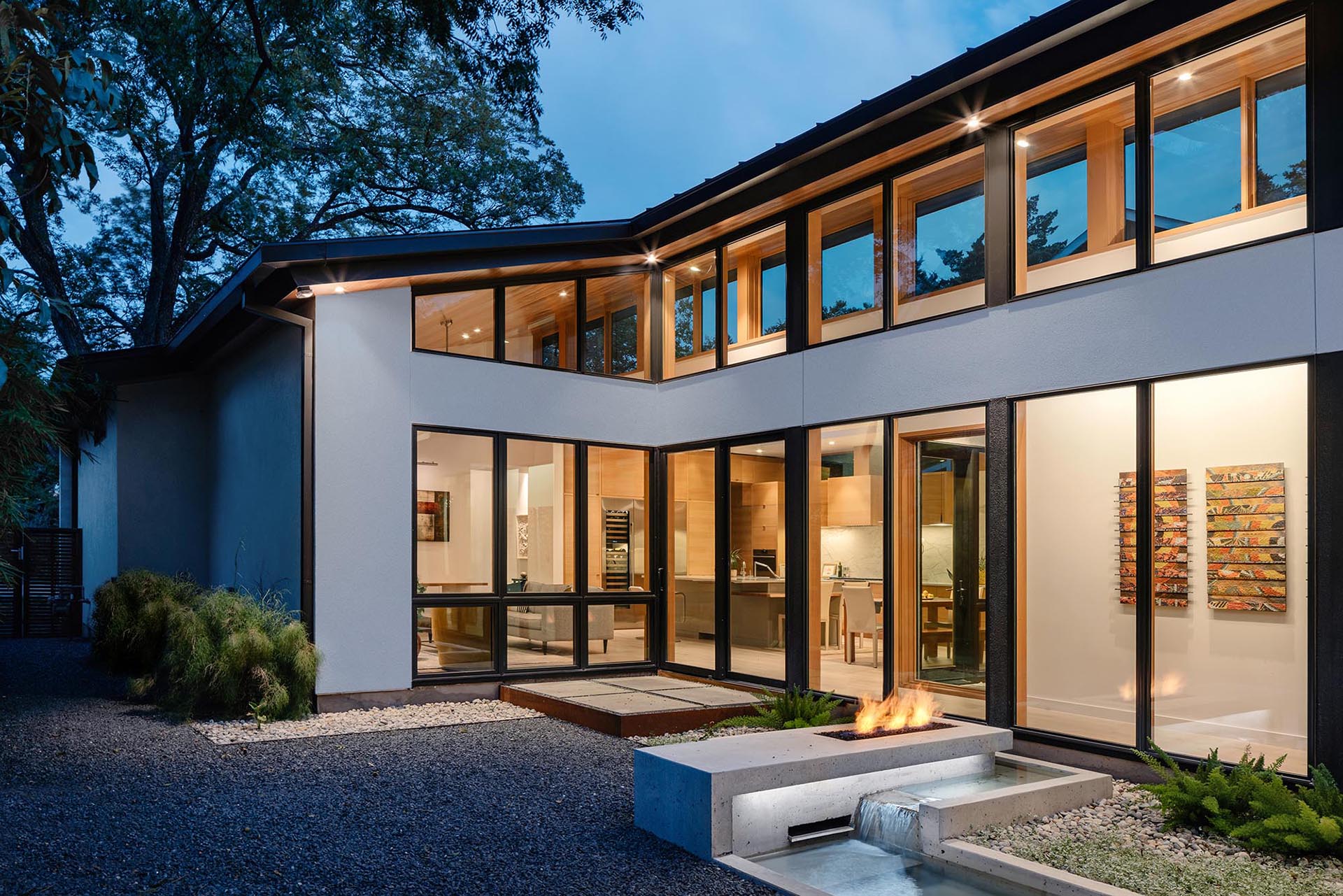 A small home with an outdoor patio that includes a water feature and fireplace.