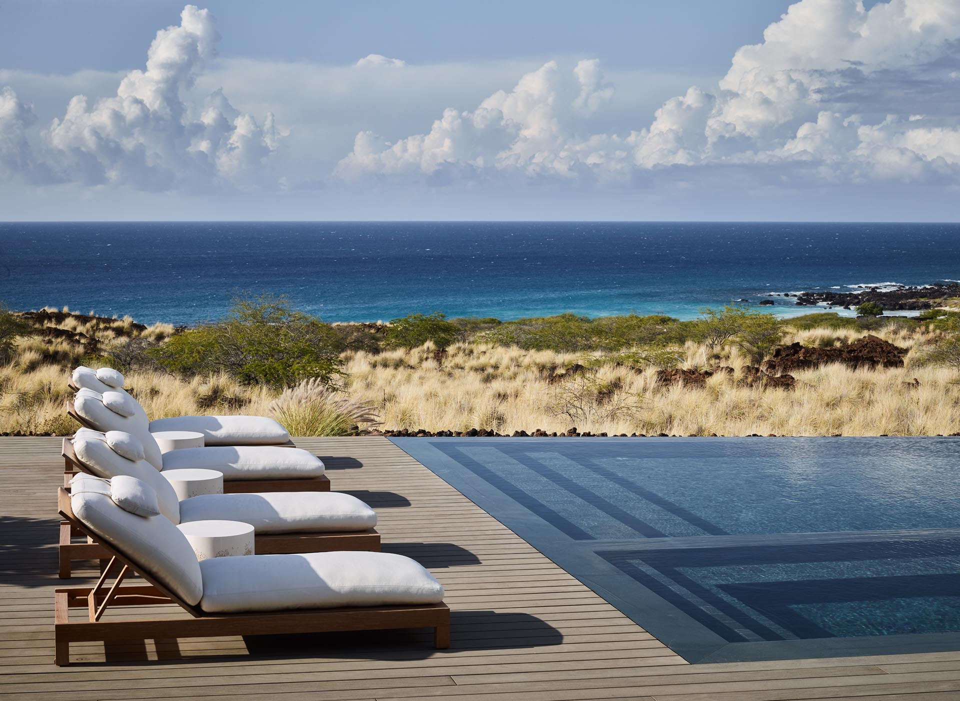 A swimming pool with a deck that overlooks the Pacific Ocean.