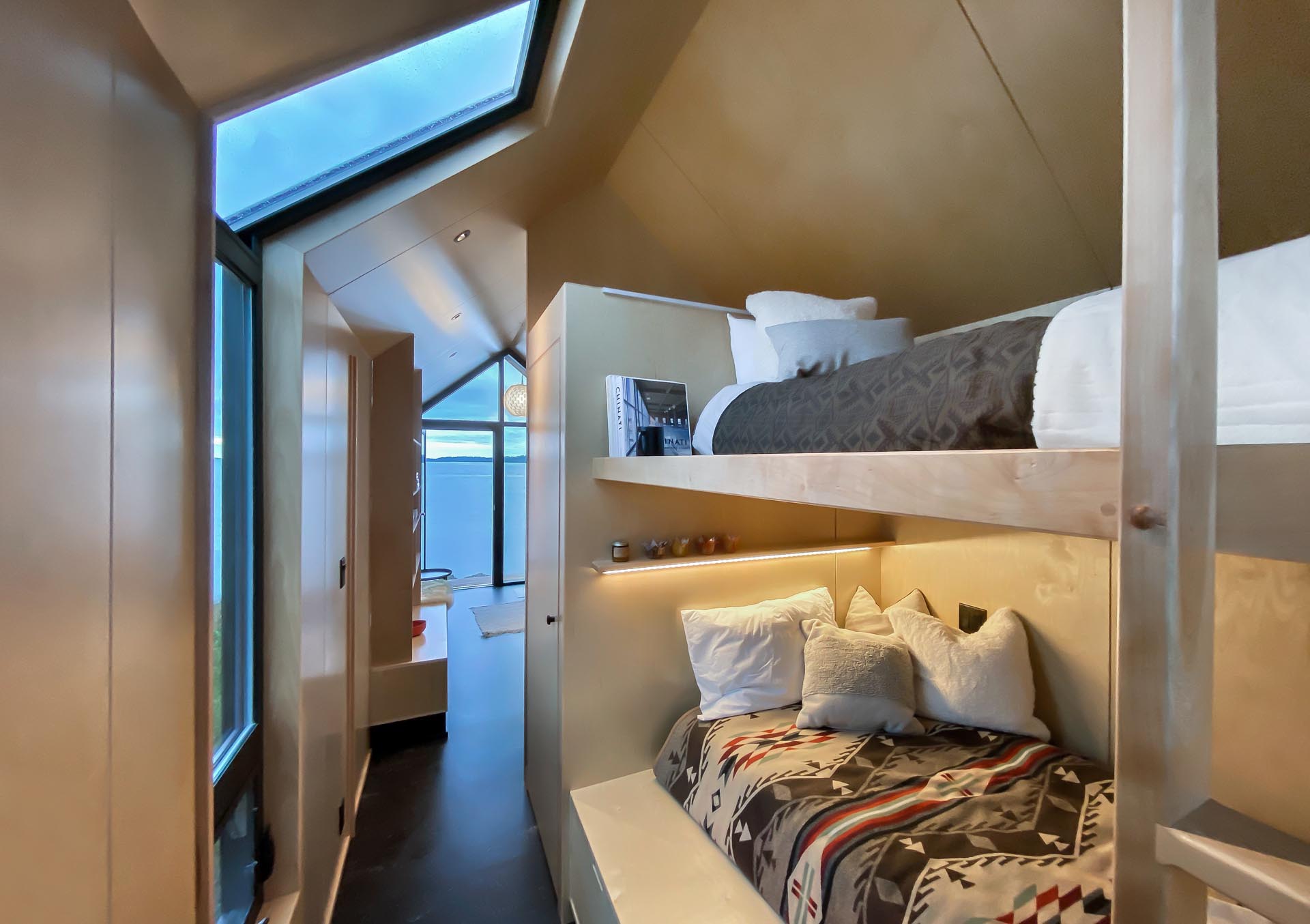 A tiny house with bunk beds that don't feel enclosed due to the gabled ceiling.