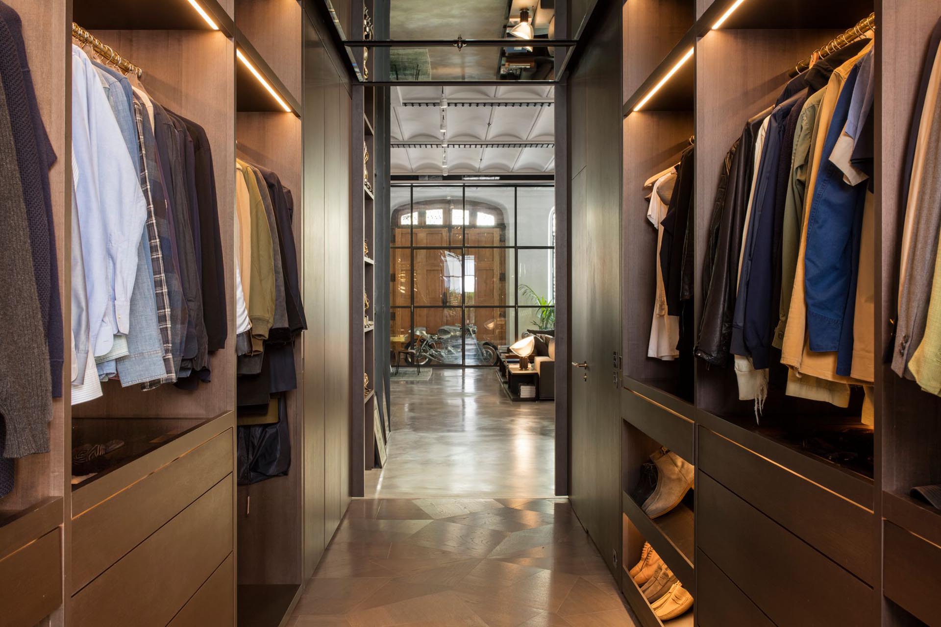 A walk-through closet with plenty of hanging space highlighted by LED strips.