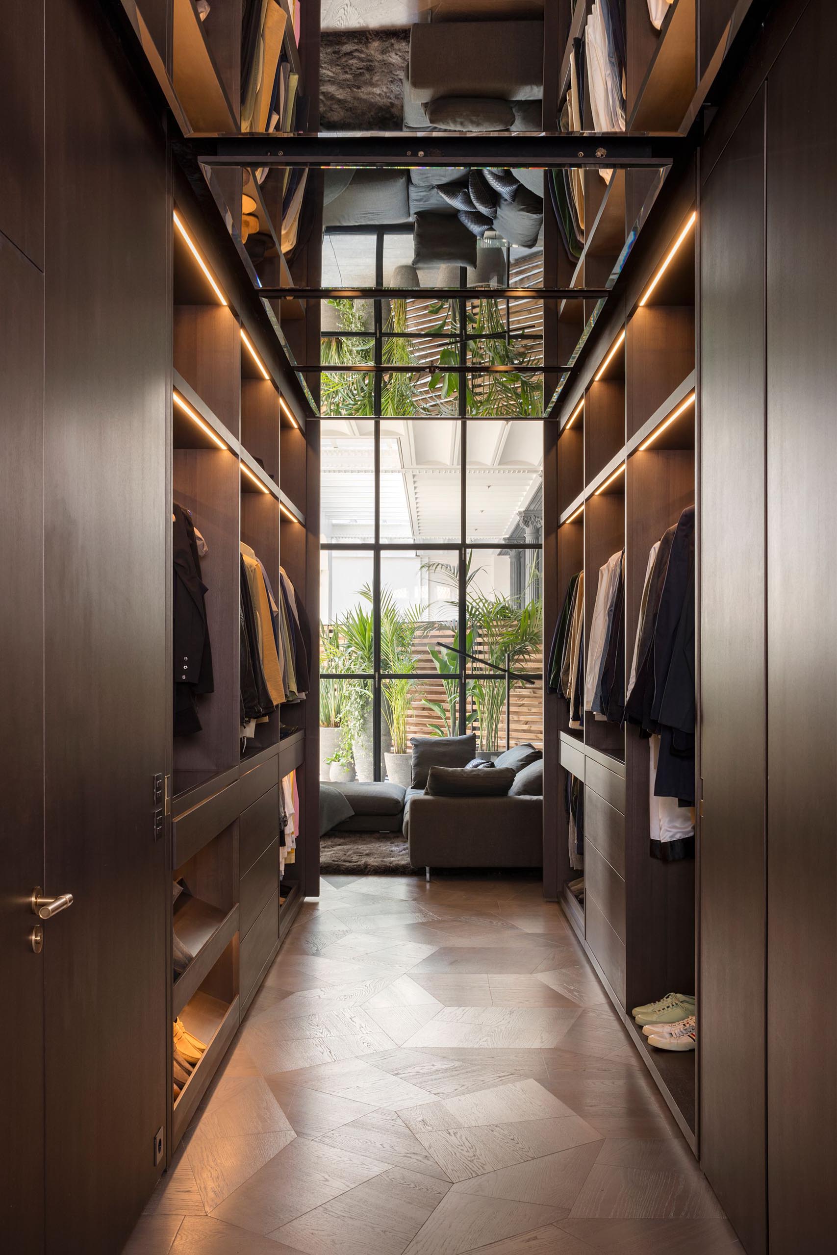 A walk-through closet with plenty of hanging space highlighted by LED strips.