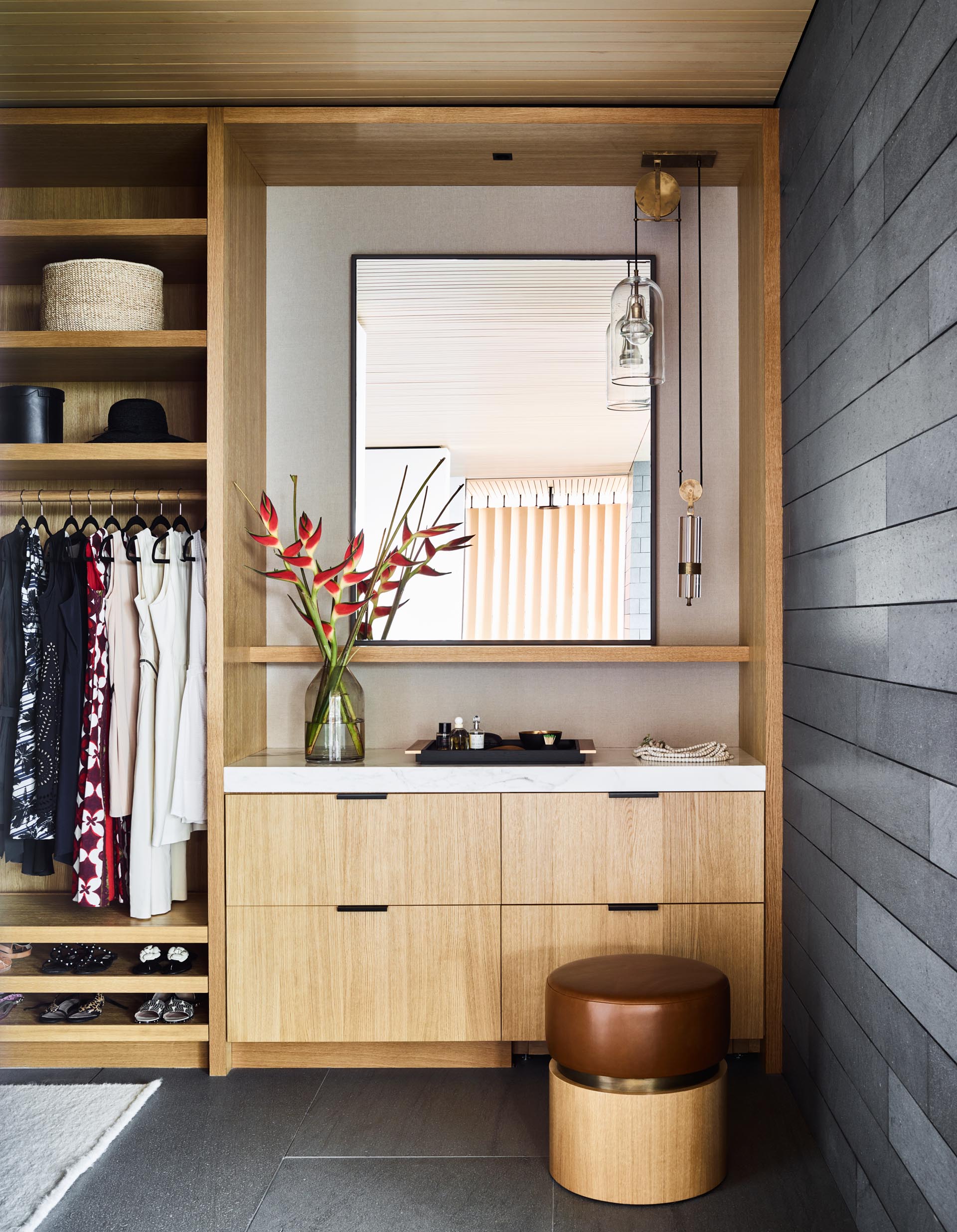 A modern walk-in closet with a vanity area, drawers, shelving, and space for hanging clothes.