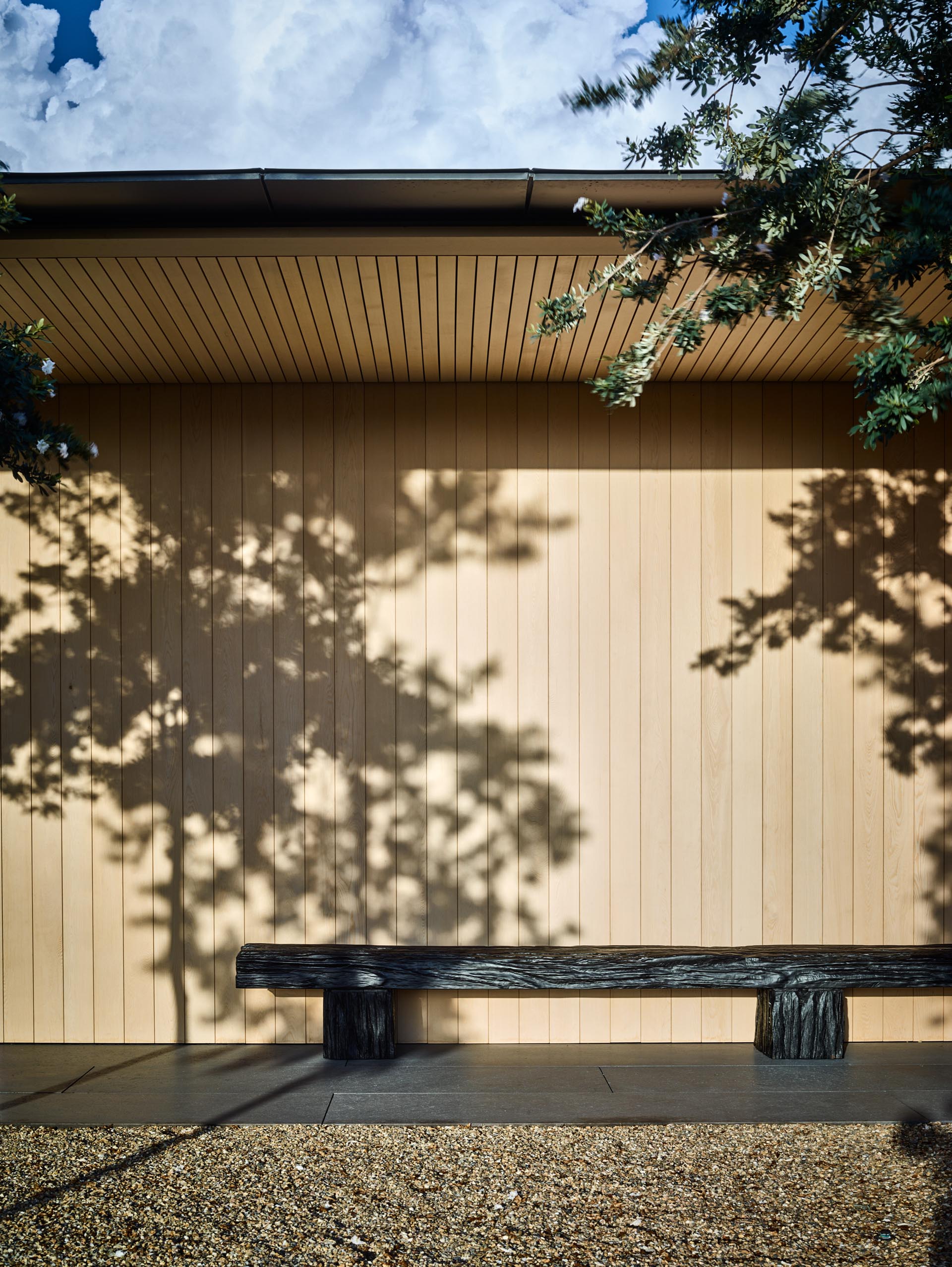 A modern home with light wood siding and a covered pathway.