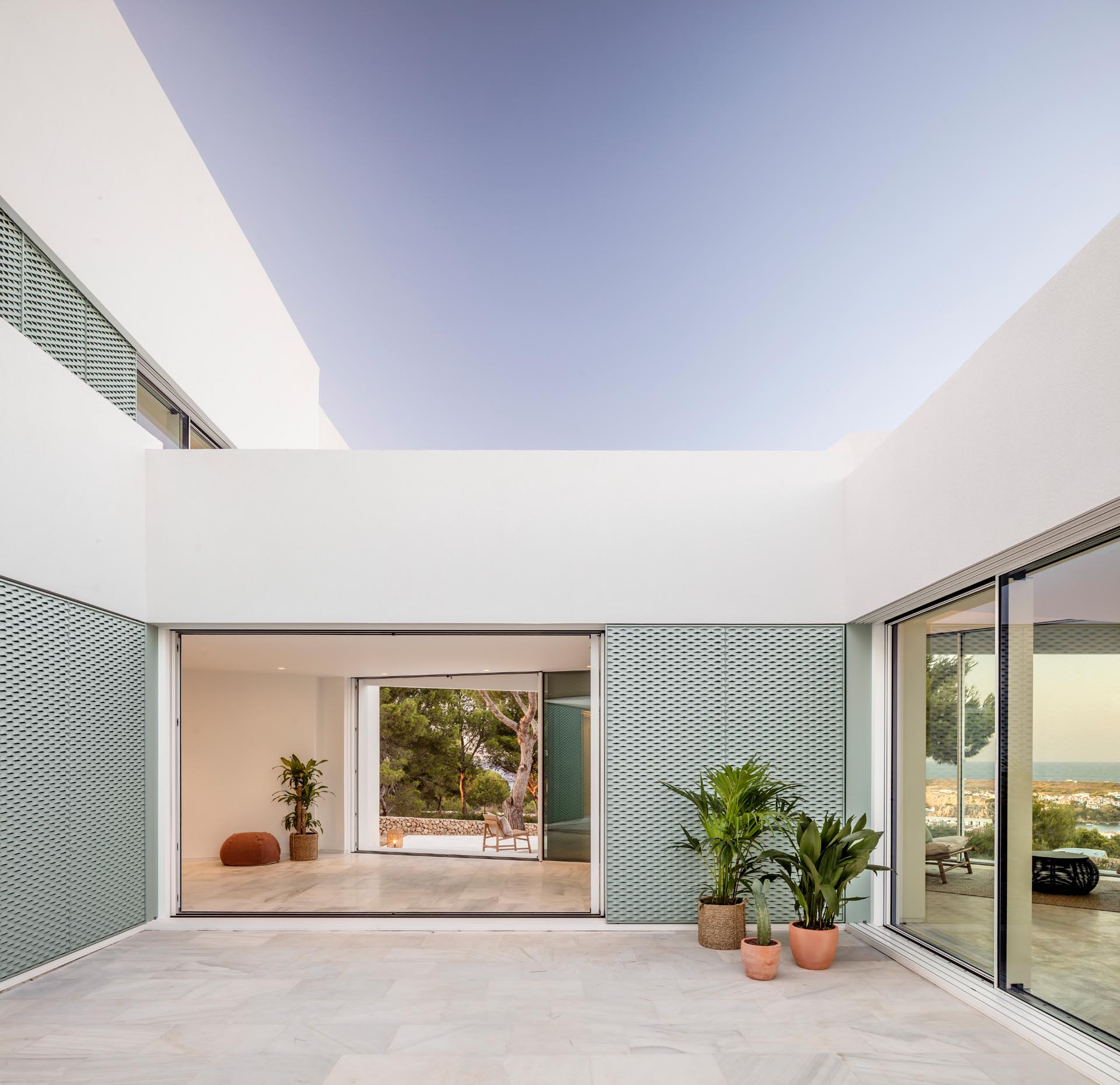 A modern white home with pastel turquoise perforated aluminum screens.