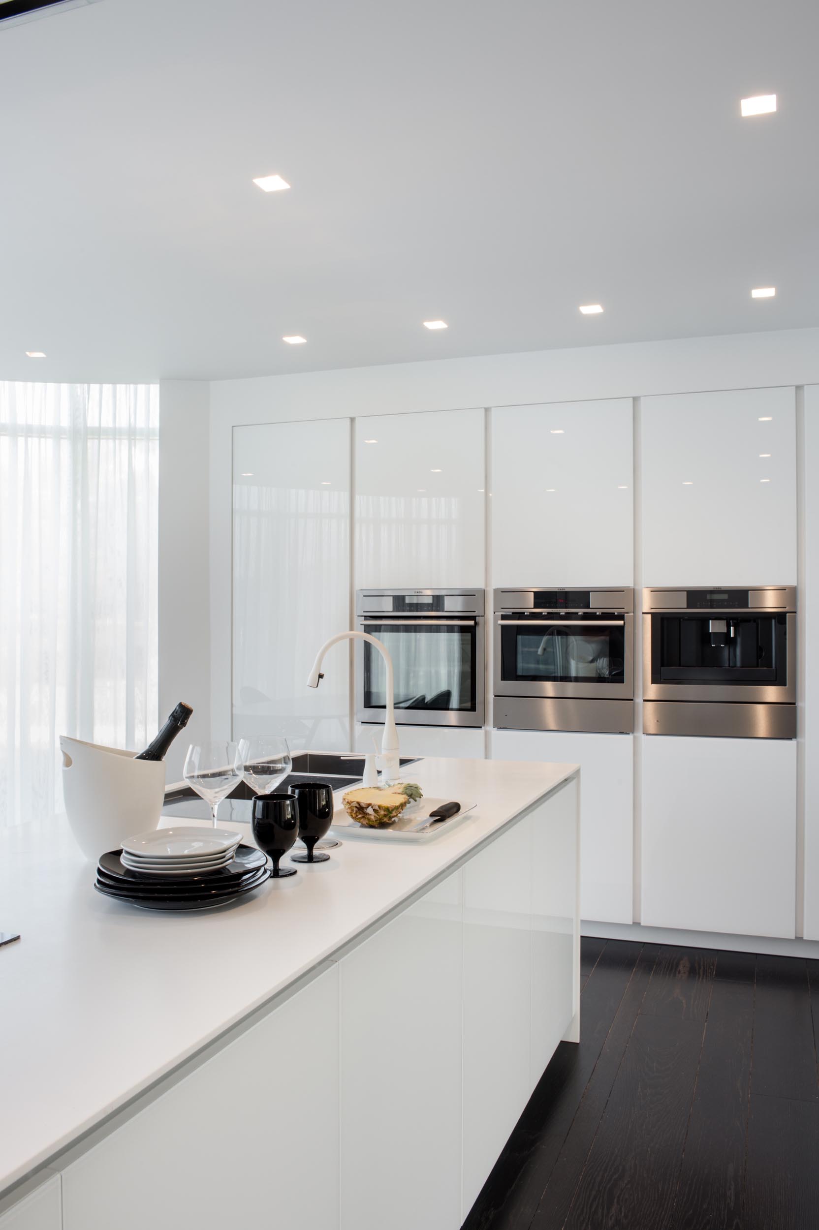 A modern kitchen with minimalist white cabinets and an island.