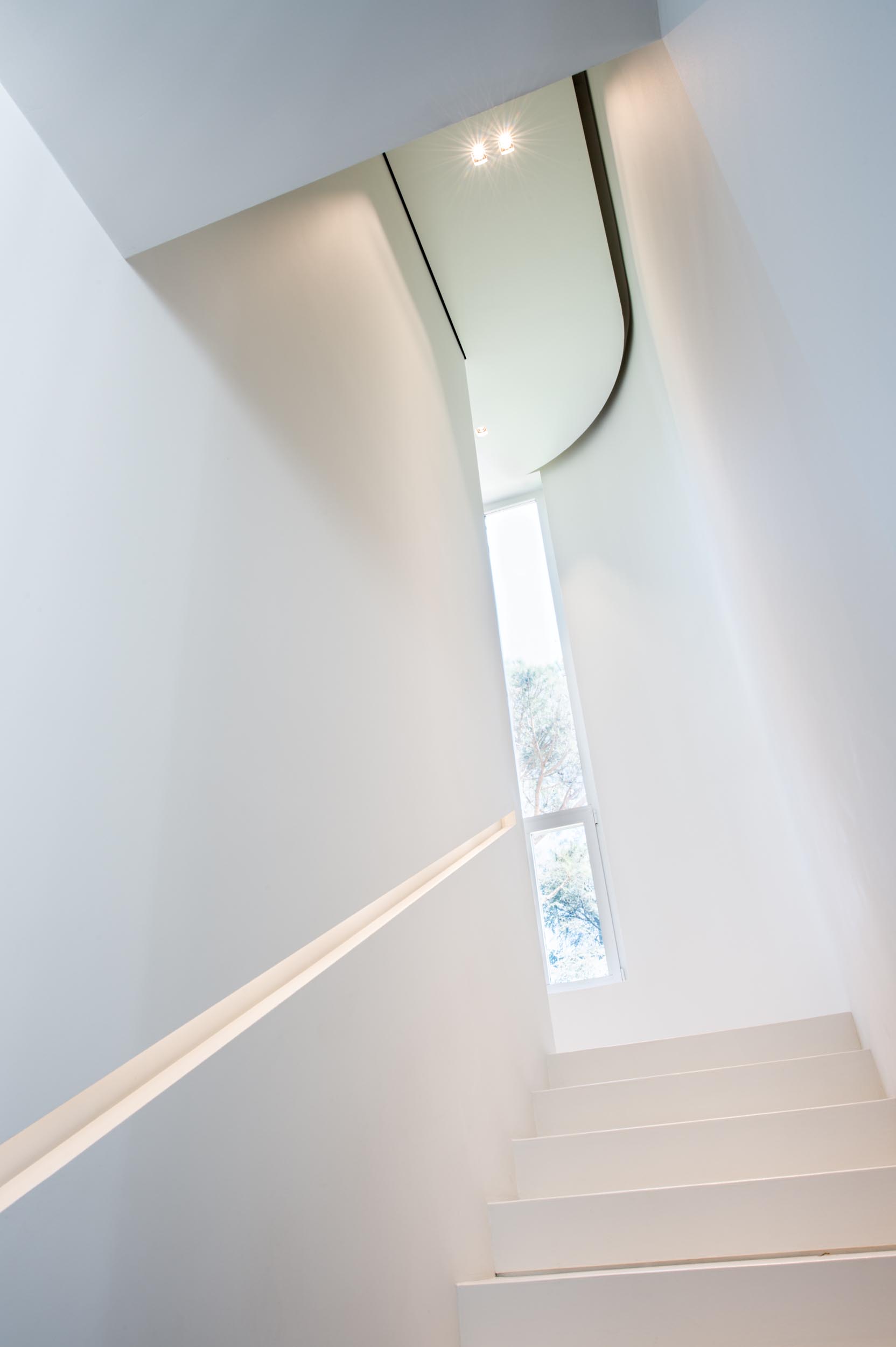 A white staircase that helps to keep the space bright, while a built-in handrail also has LED lighting hidden from view.