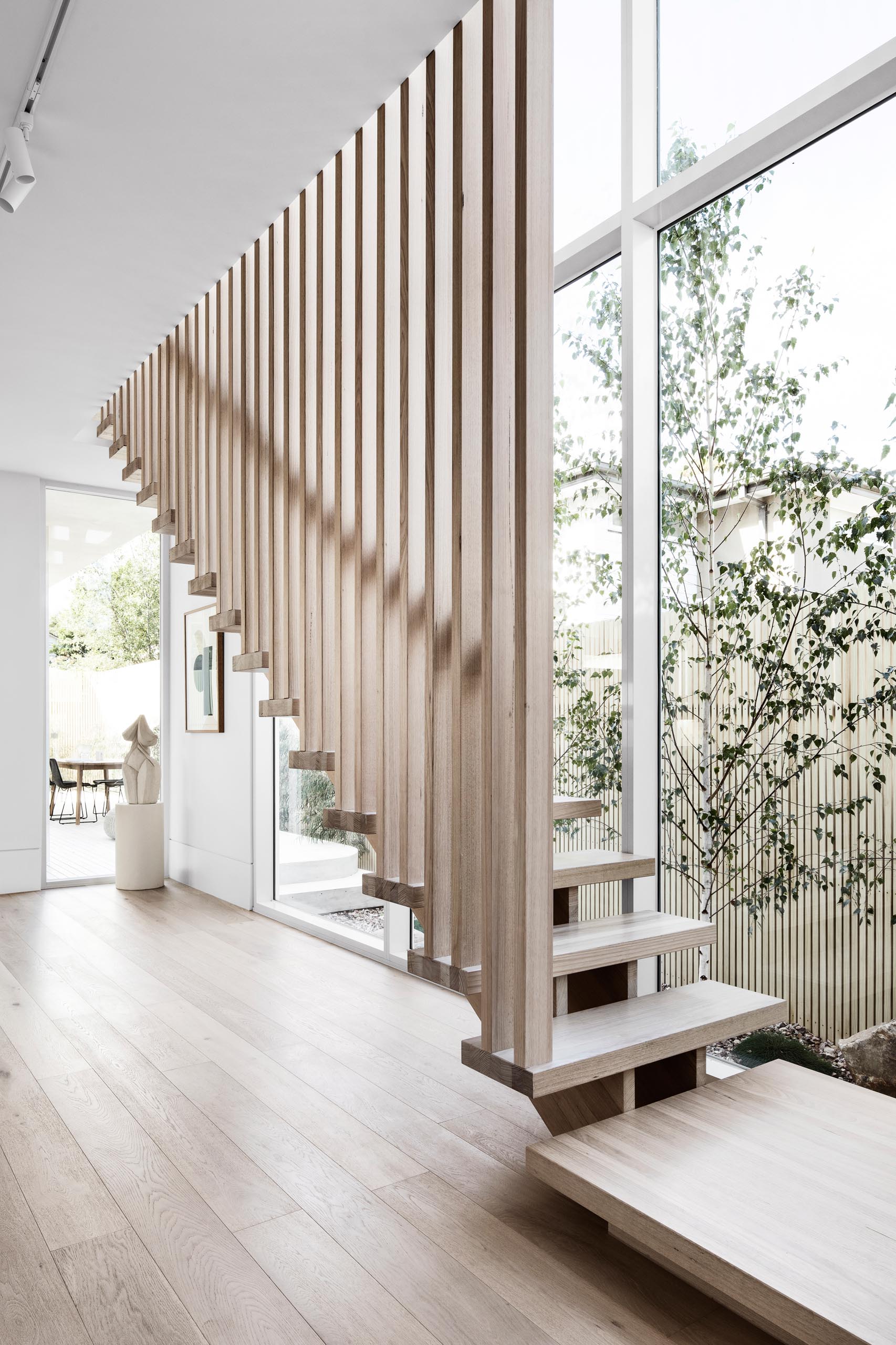 This modern staircase was located beside a wall of windows and has an overall muted, minimalist, light theme that was achieved by using natural Victorian ash timber on the treads and battens.