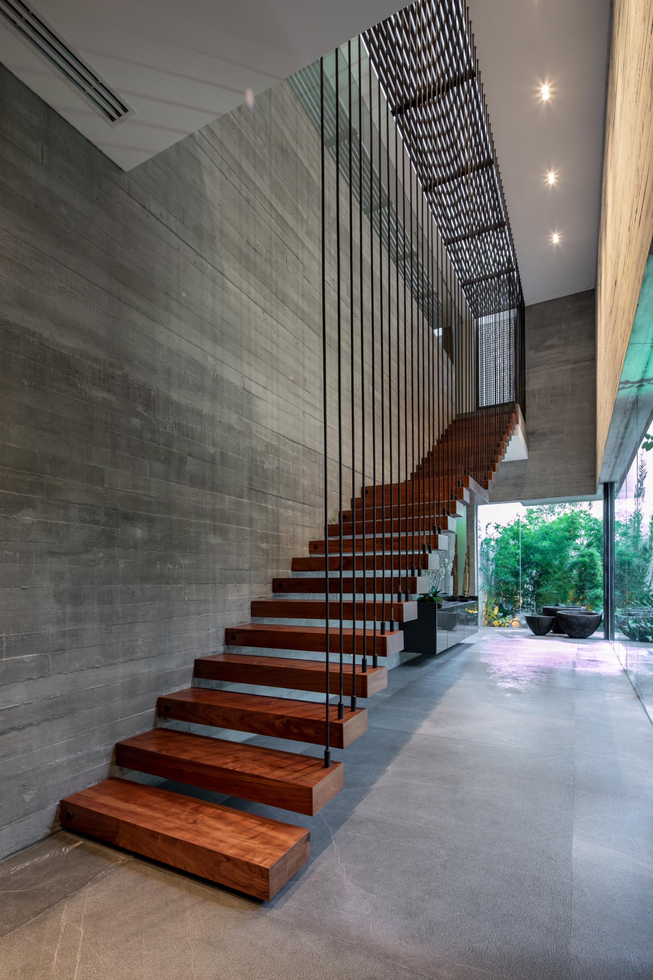 A board-formed concrete wall is visible alongside a wood staircase, which also lights up at night.