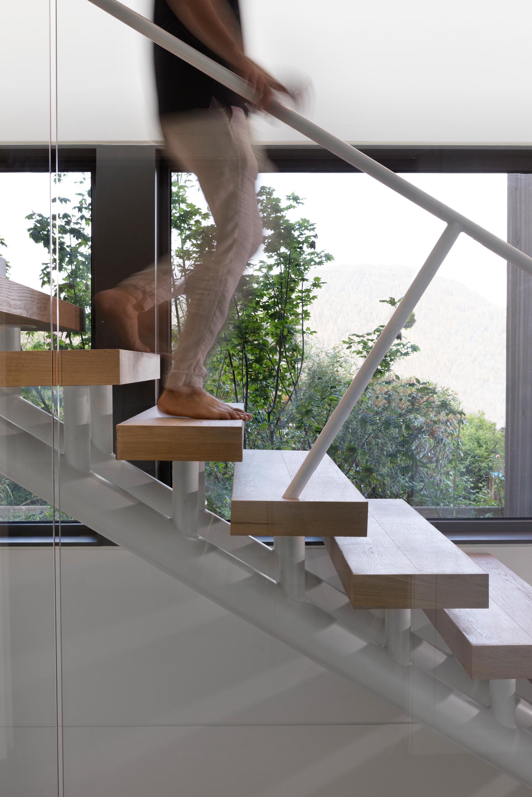 Wood stairs treads are supported by a white frame, while glass has been used as a safety feature and also allows the light from the window to flow through to the interior.