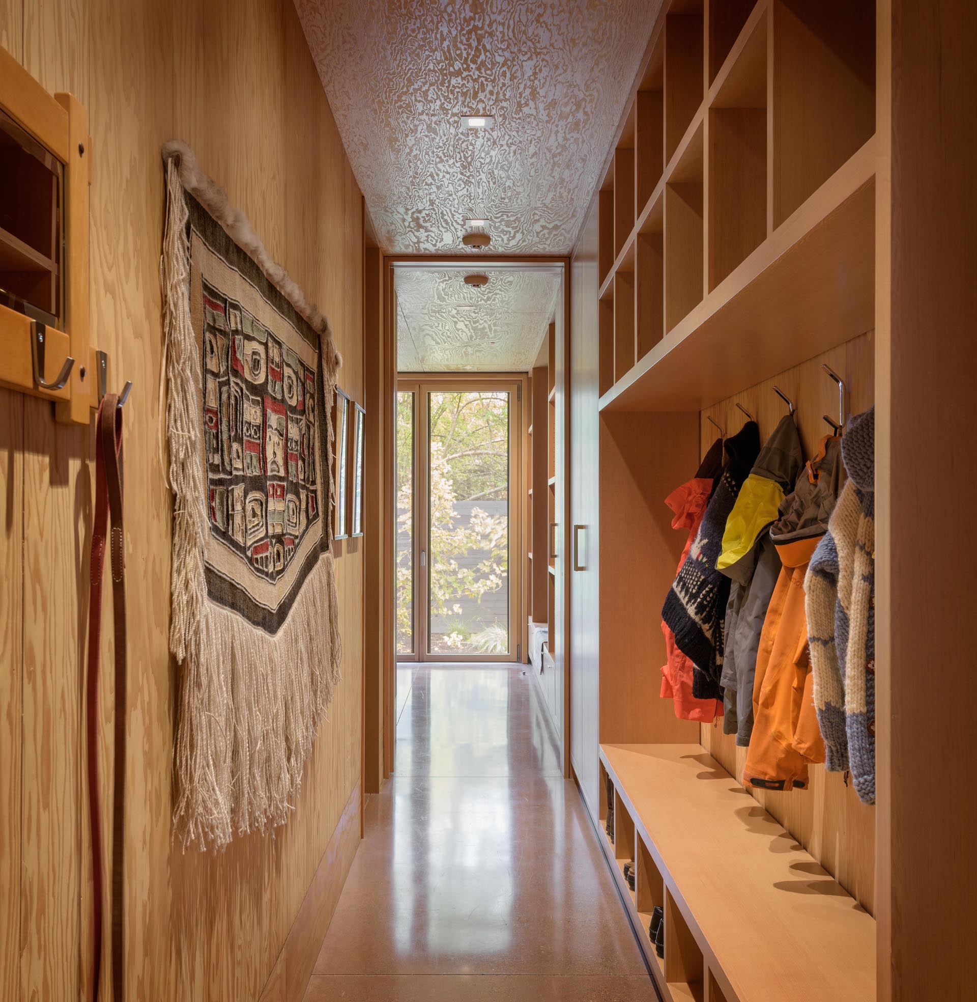 A hallway with a custom-built shelving that doubles as a mudroom.