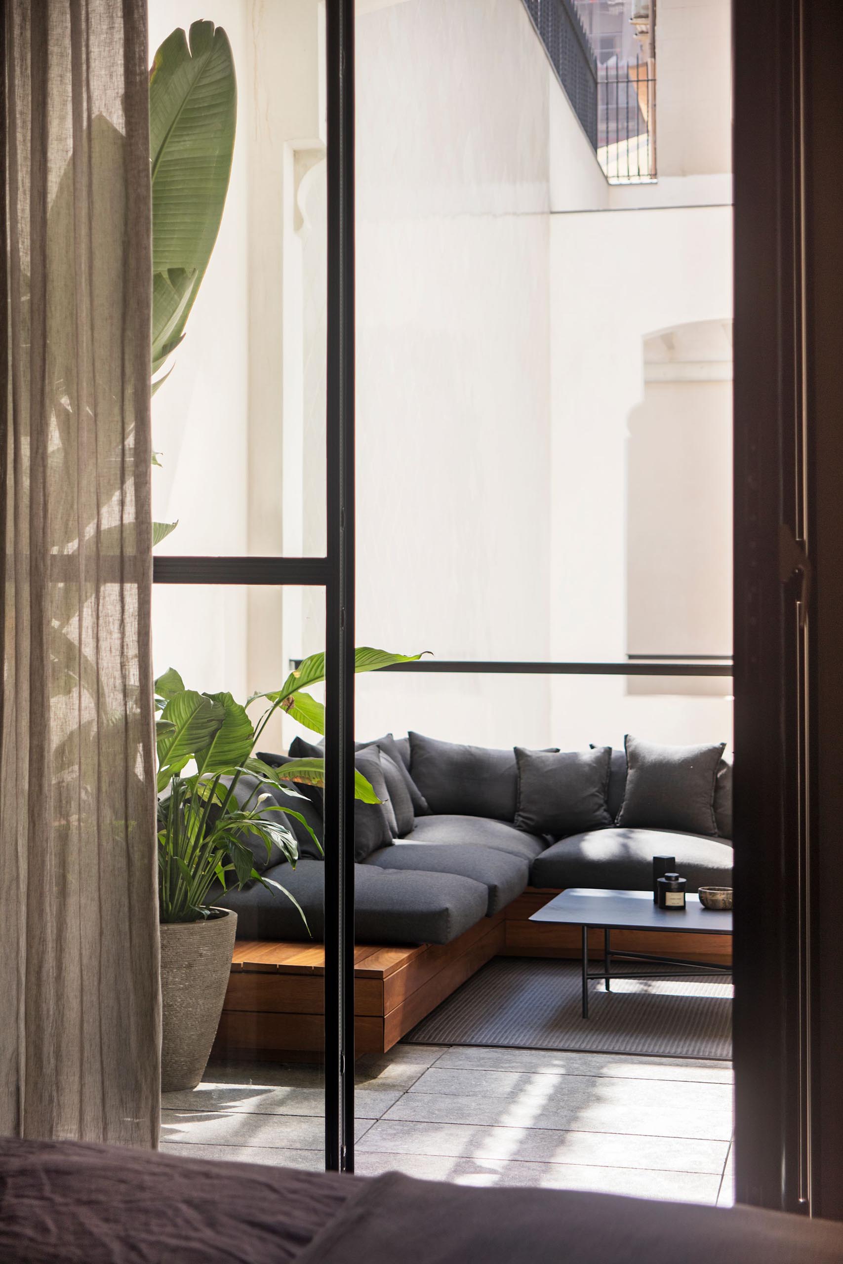 A modern sunroom with an L-shaped sofa and potted plants.