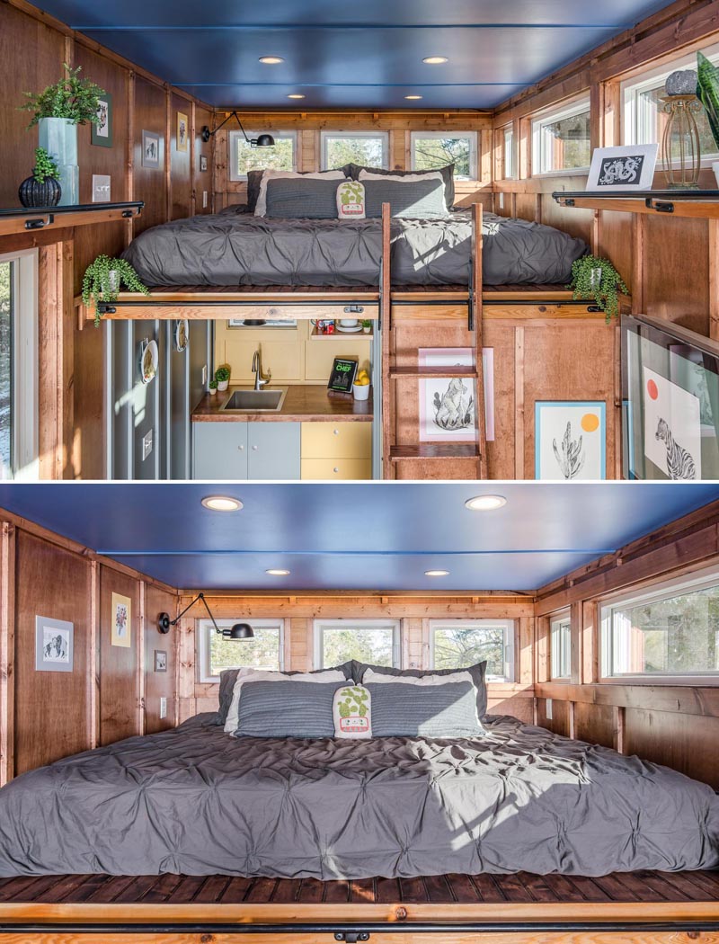 The sleeping loft of this tiny home, which has a king sized bed with a 270-degree view, is located above the kitchen and bathroom and is accessed via a ladder.