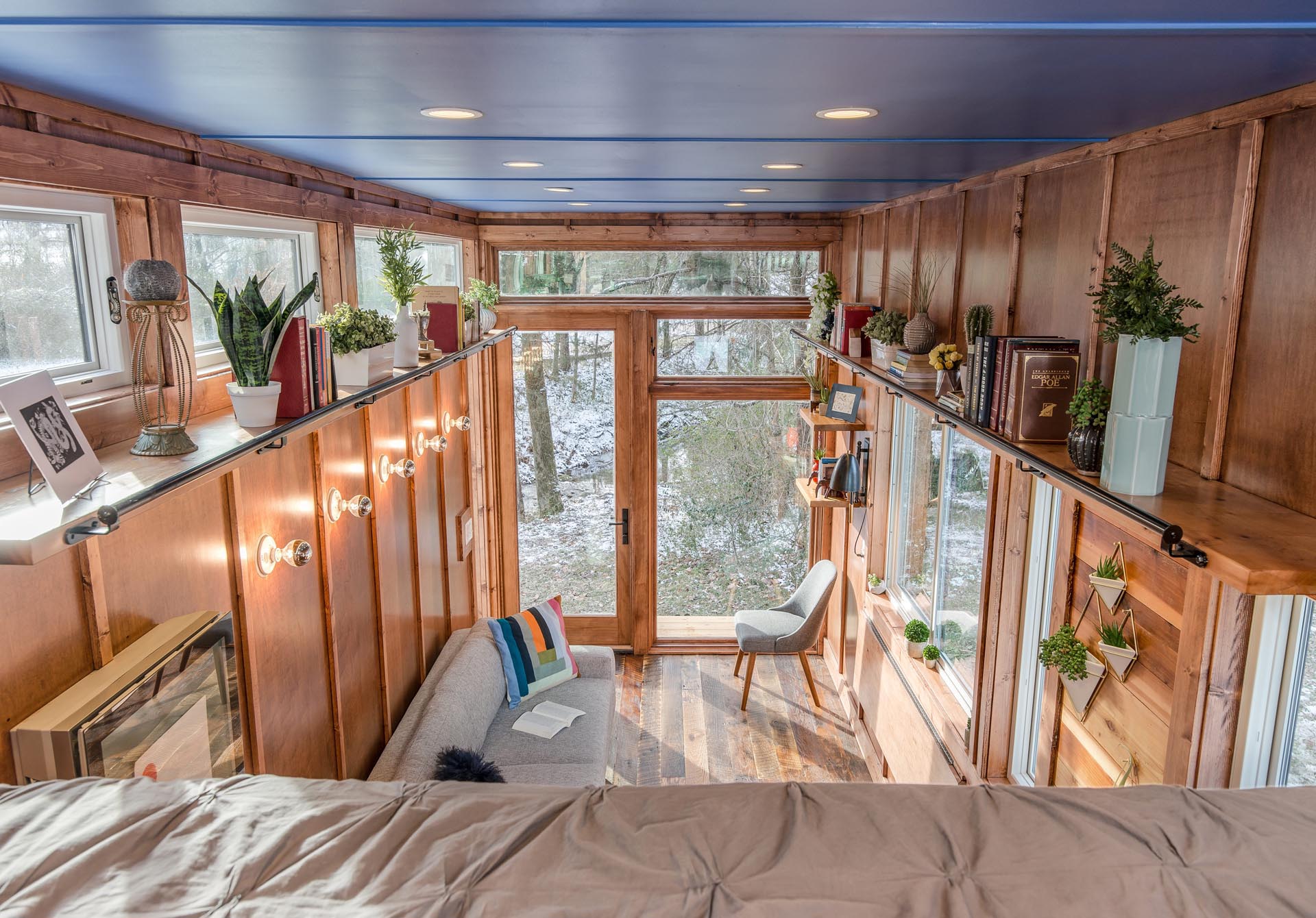 This tiny house has floating cedar library shelves with a rolling ladder.