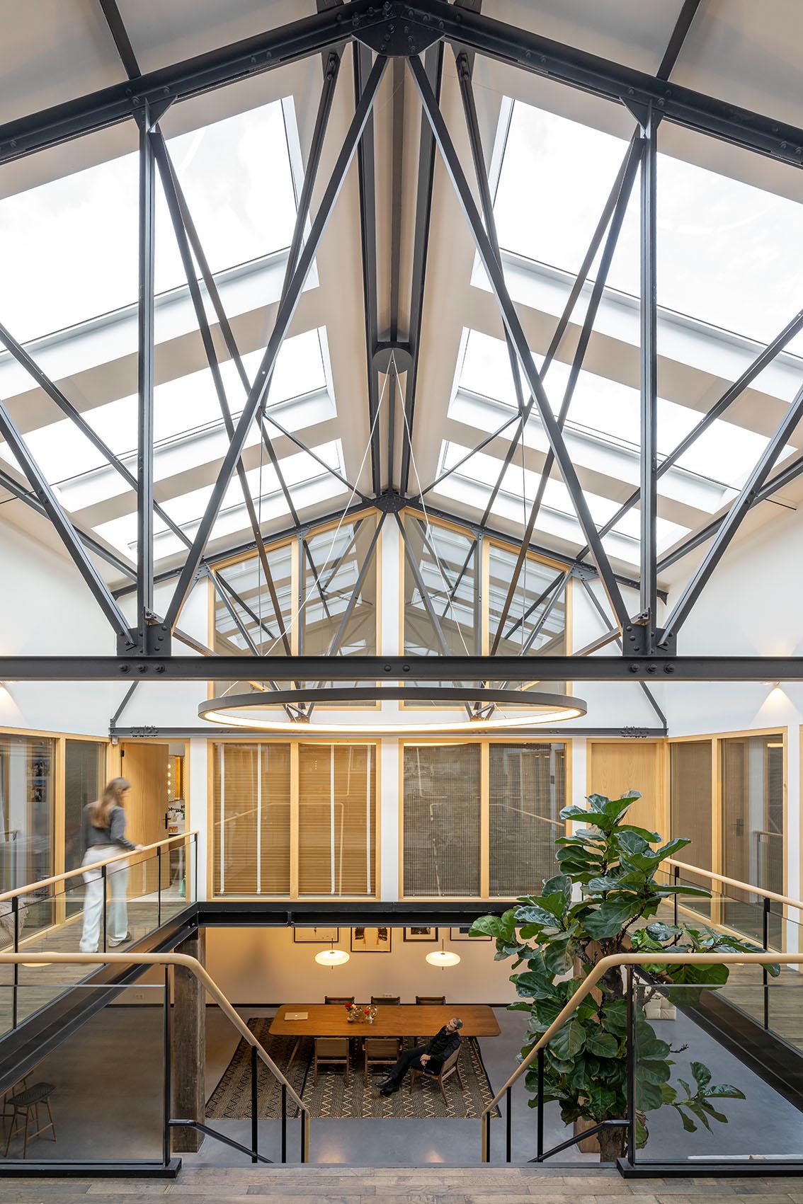 A remodeled gymnasium with 10 large skylights, black trusses, an open walkway and a large open plan main floor.