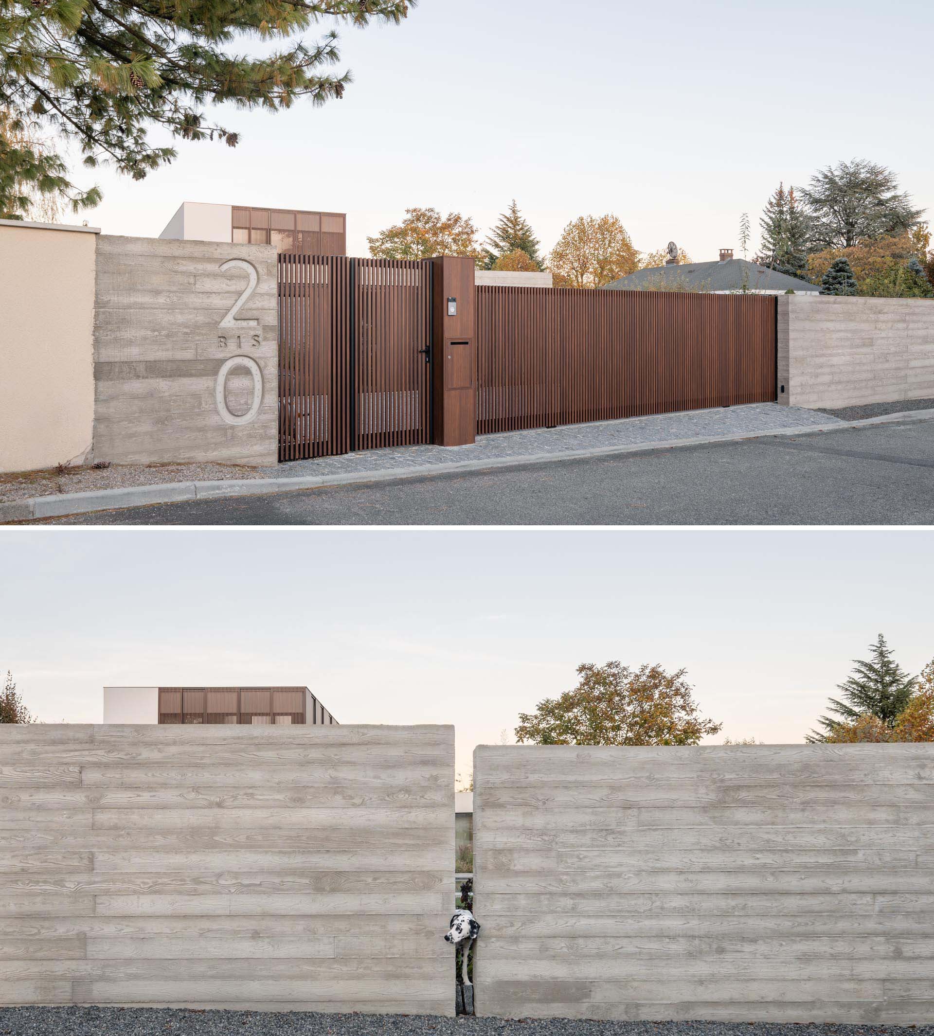 A modern concrete front wall with wood gate and driveway access.