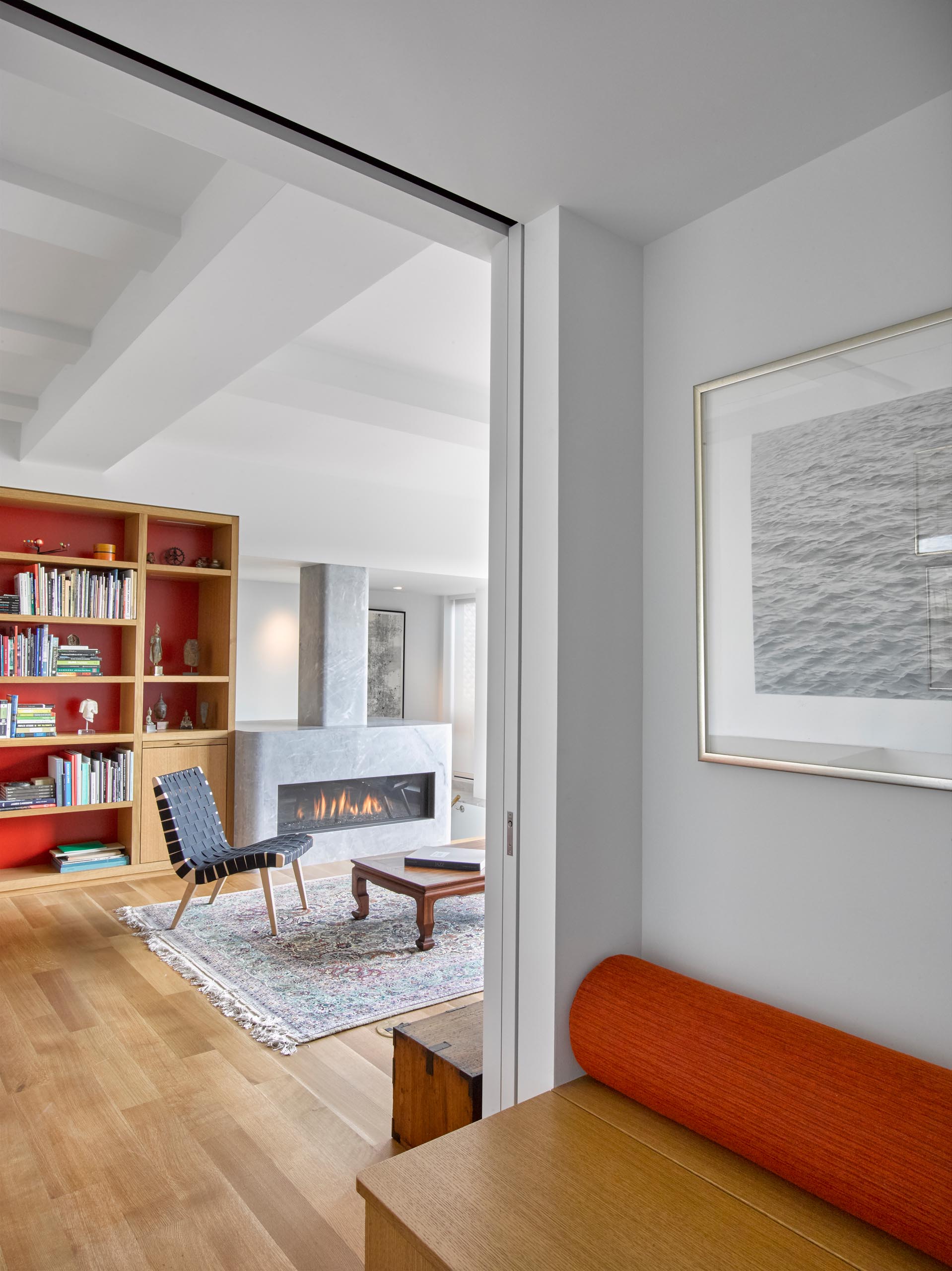 A modern living room with custom shelving and a grey stone fireplace surround.