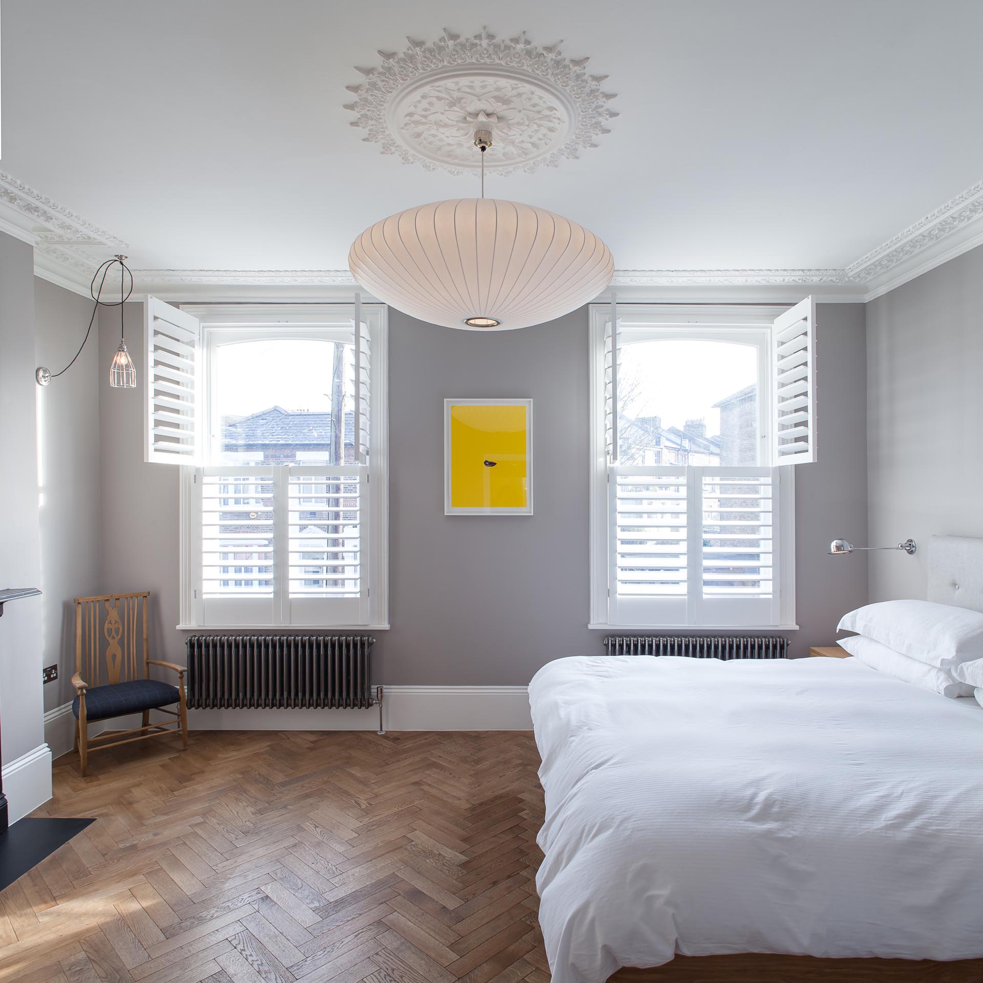 A contemporary bedroom with gray walls accented by white trim and window shutters.