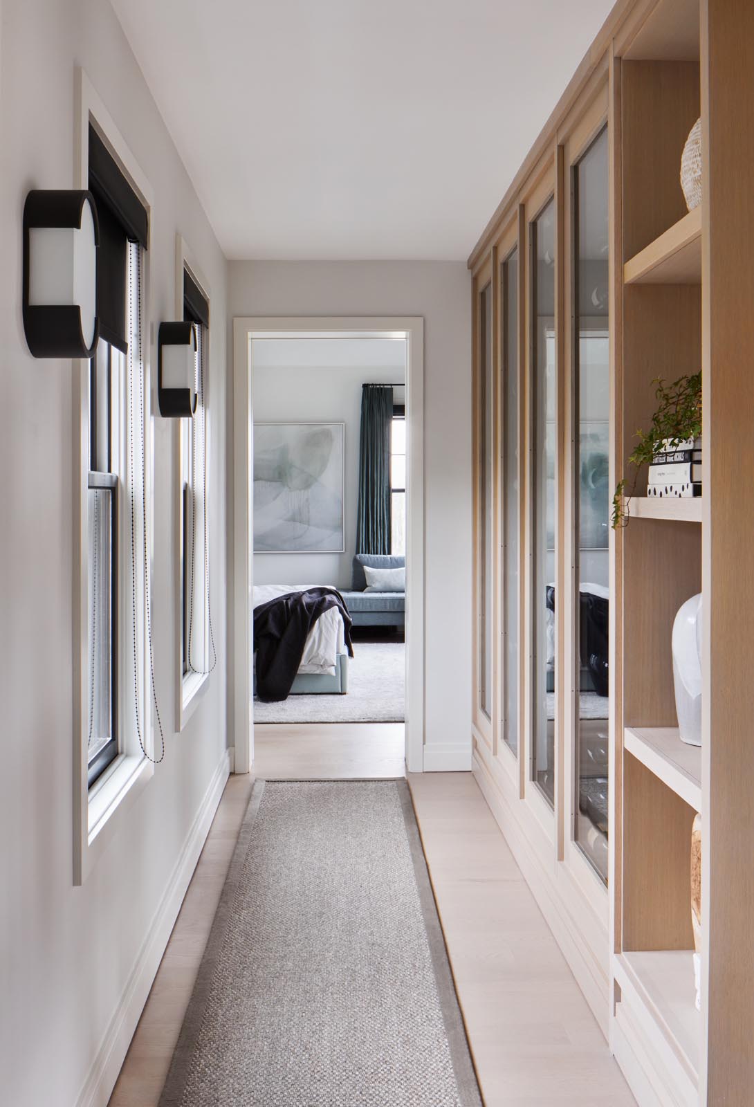 A hallway lined with wood shelving and cabinets leads to the master bedroom.