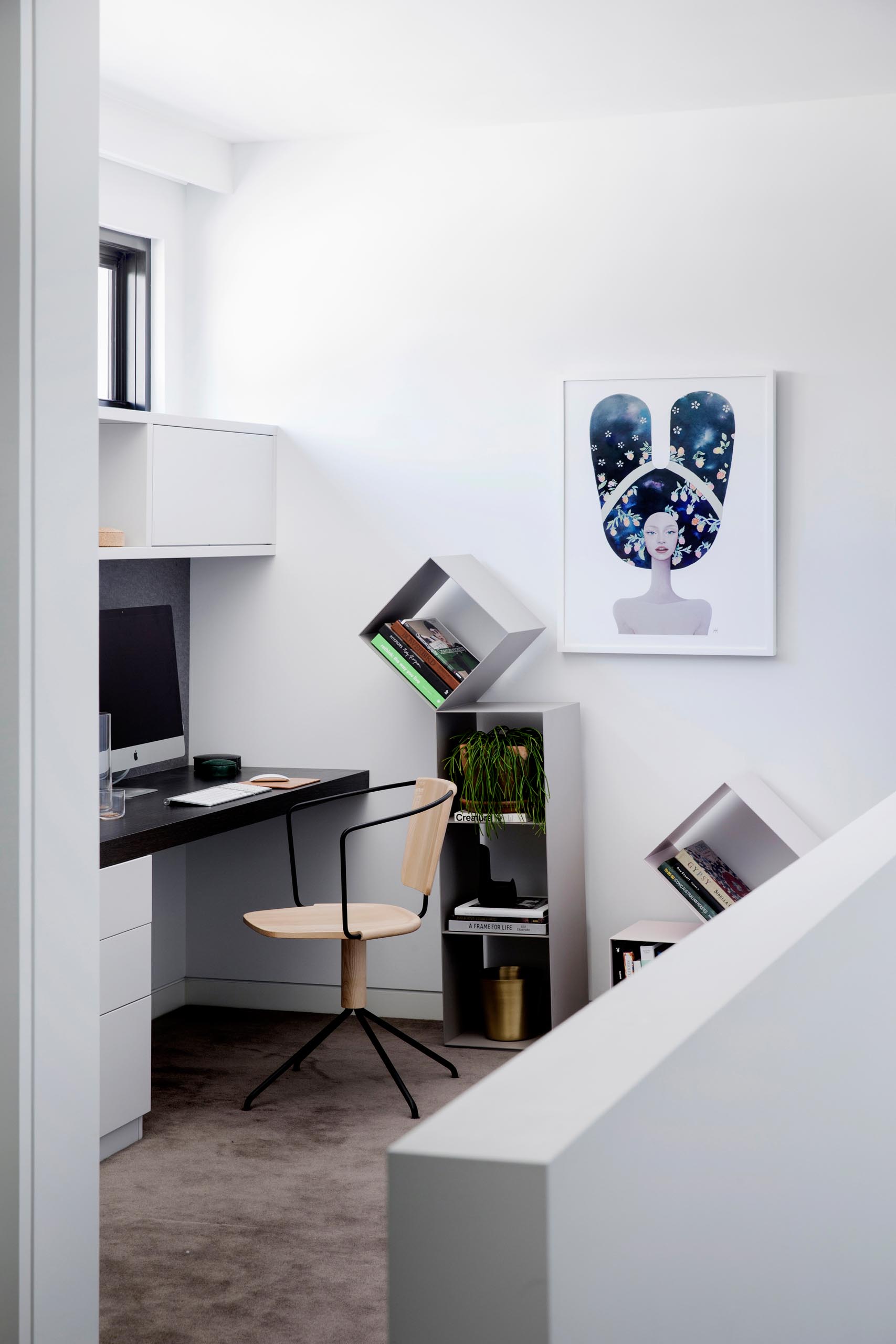 A home office nook with a custom desk and cabinets, and freestanding bookshelves.