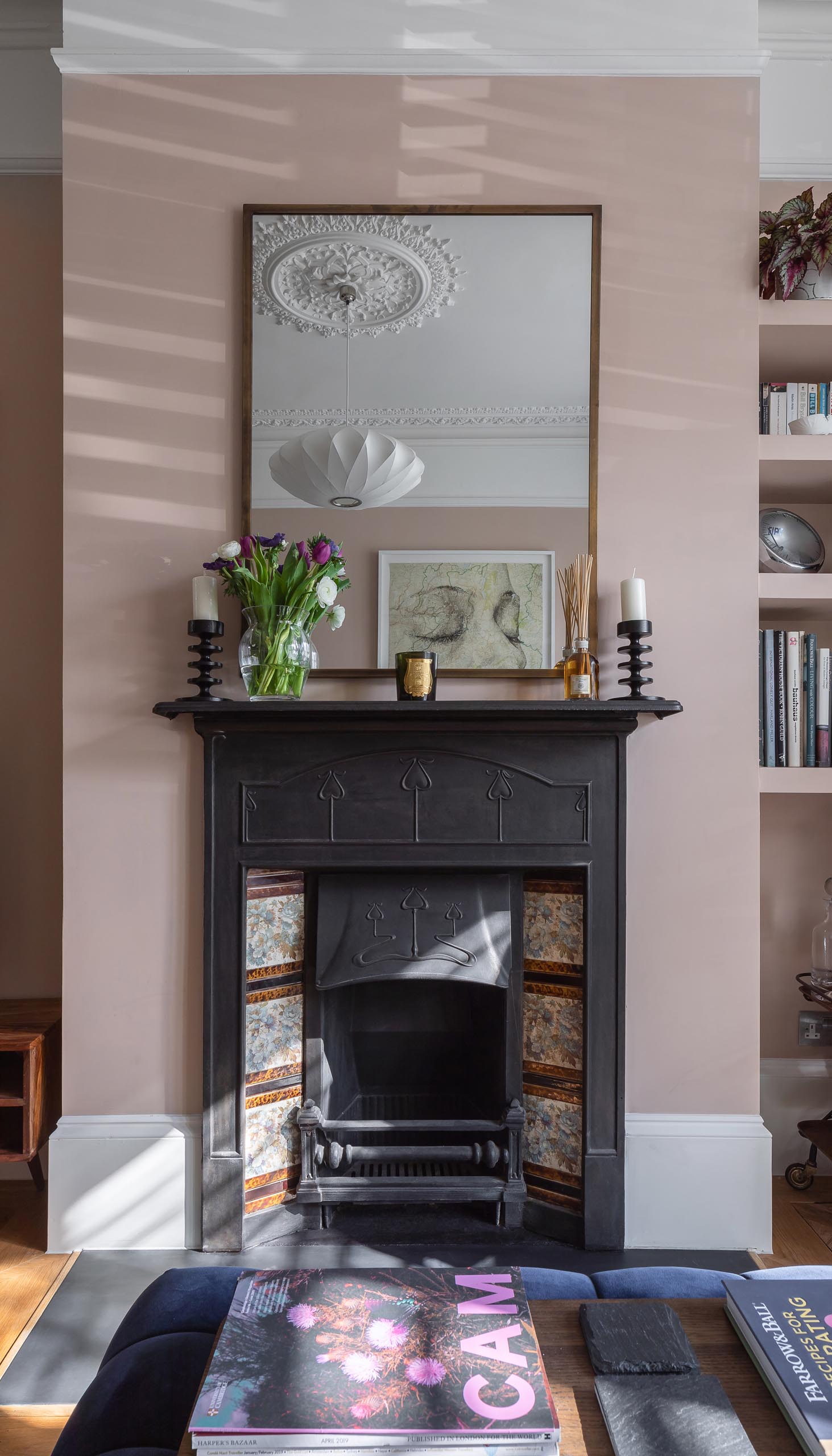 A living room with blush pink walls, contemporary furniture, built-in shelving, and a fireplace.