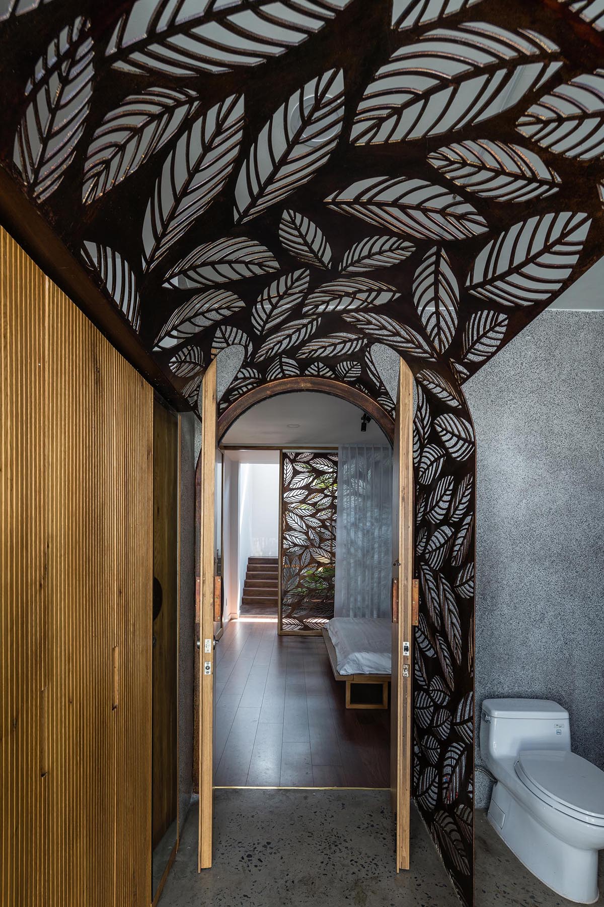 In this modern bathrooms, a decorative metal screen with a leaf motif has been used as a backdrop for vanity and as a way to highlight the doorway.