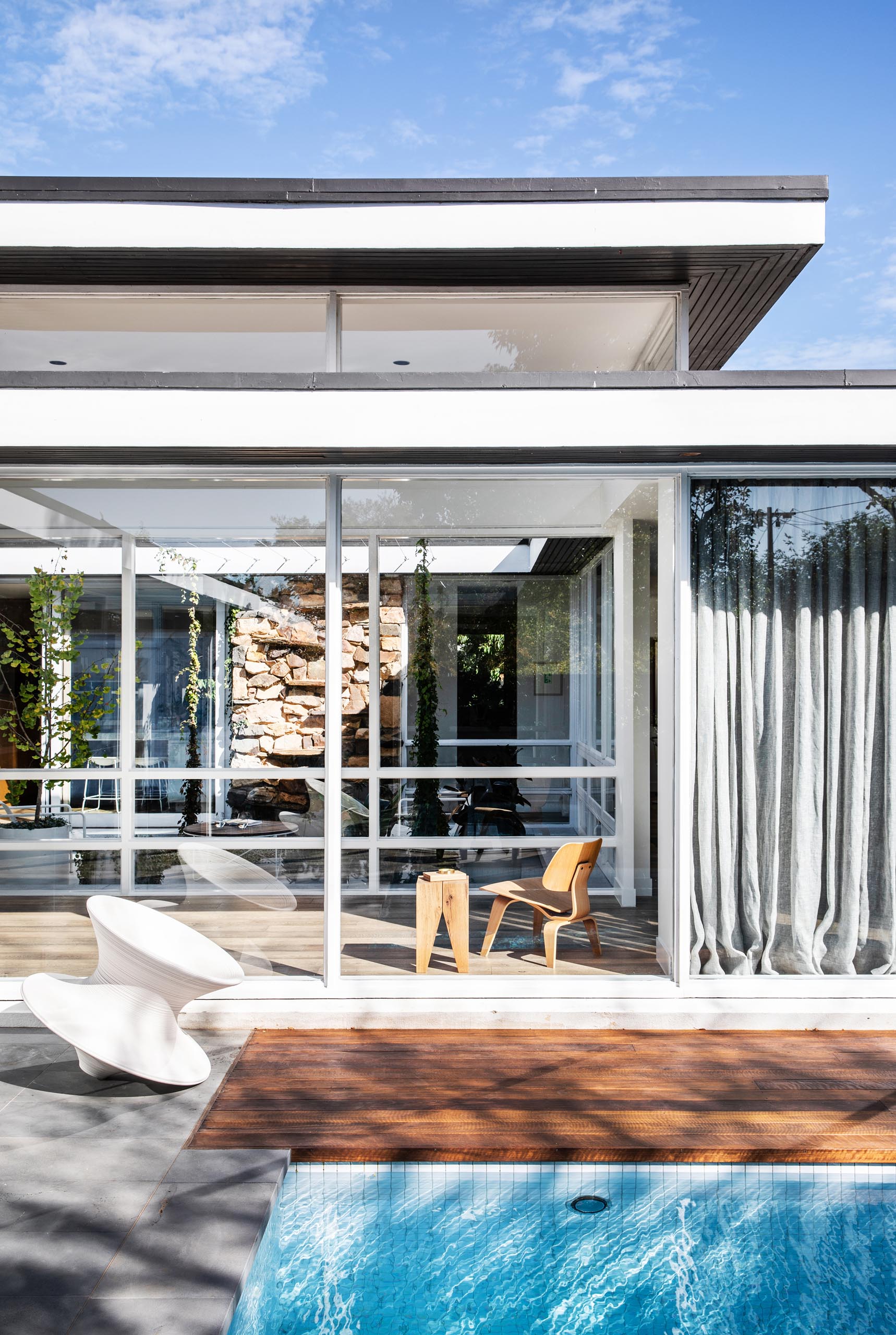 A mid century modern house with a swimming pool and floor-to-ceiling windows.