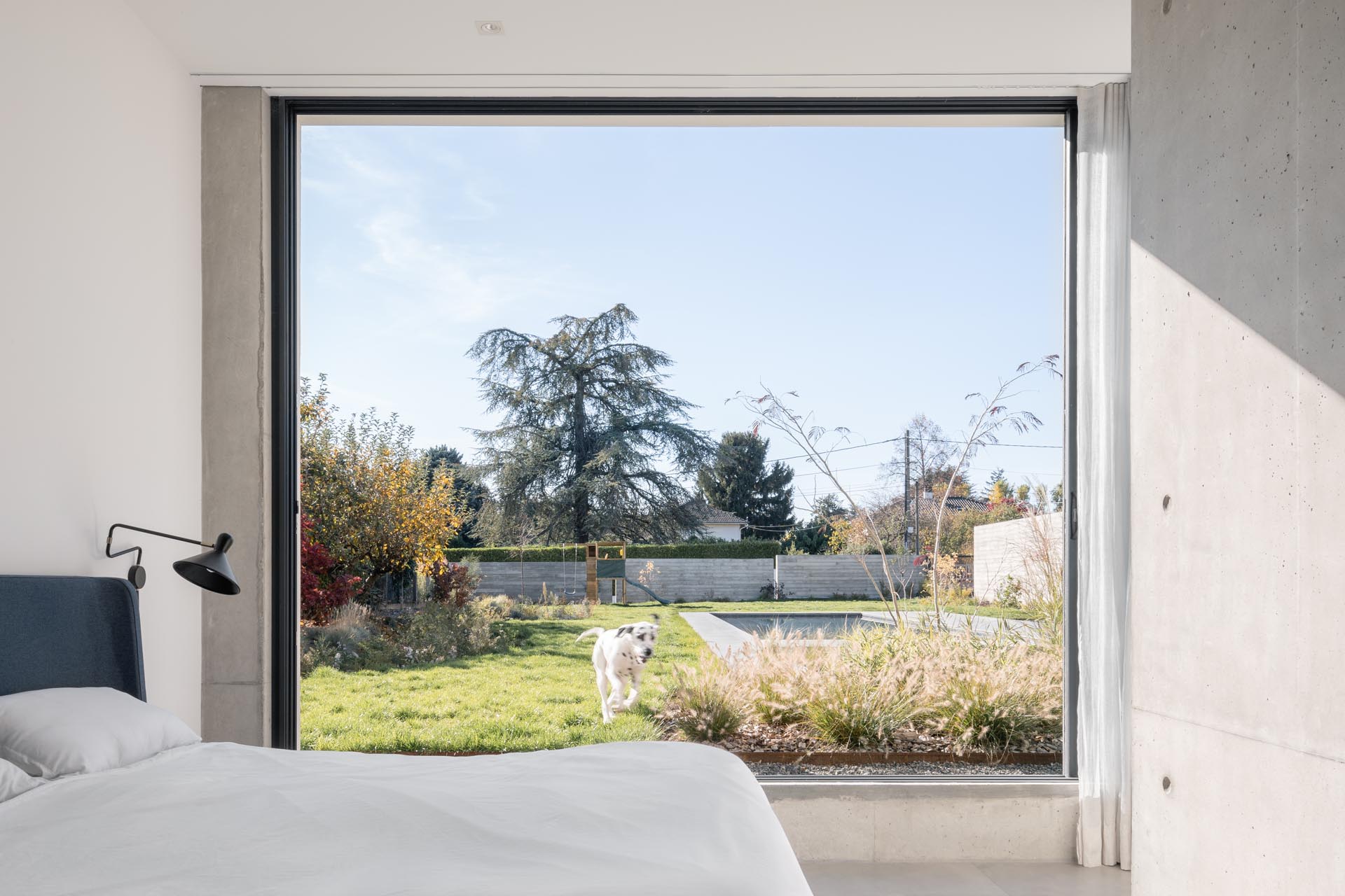 A modern bedroom with a large window that opens to the backyard.