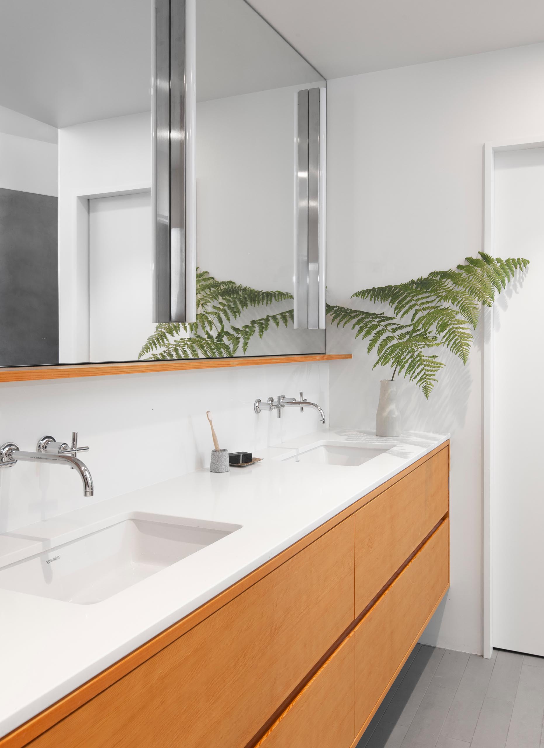 In this modern master bathroom, a Caesarstone 'Pure White' countertop sits atop a fir vanity with recessed pulls.