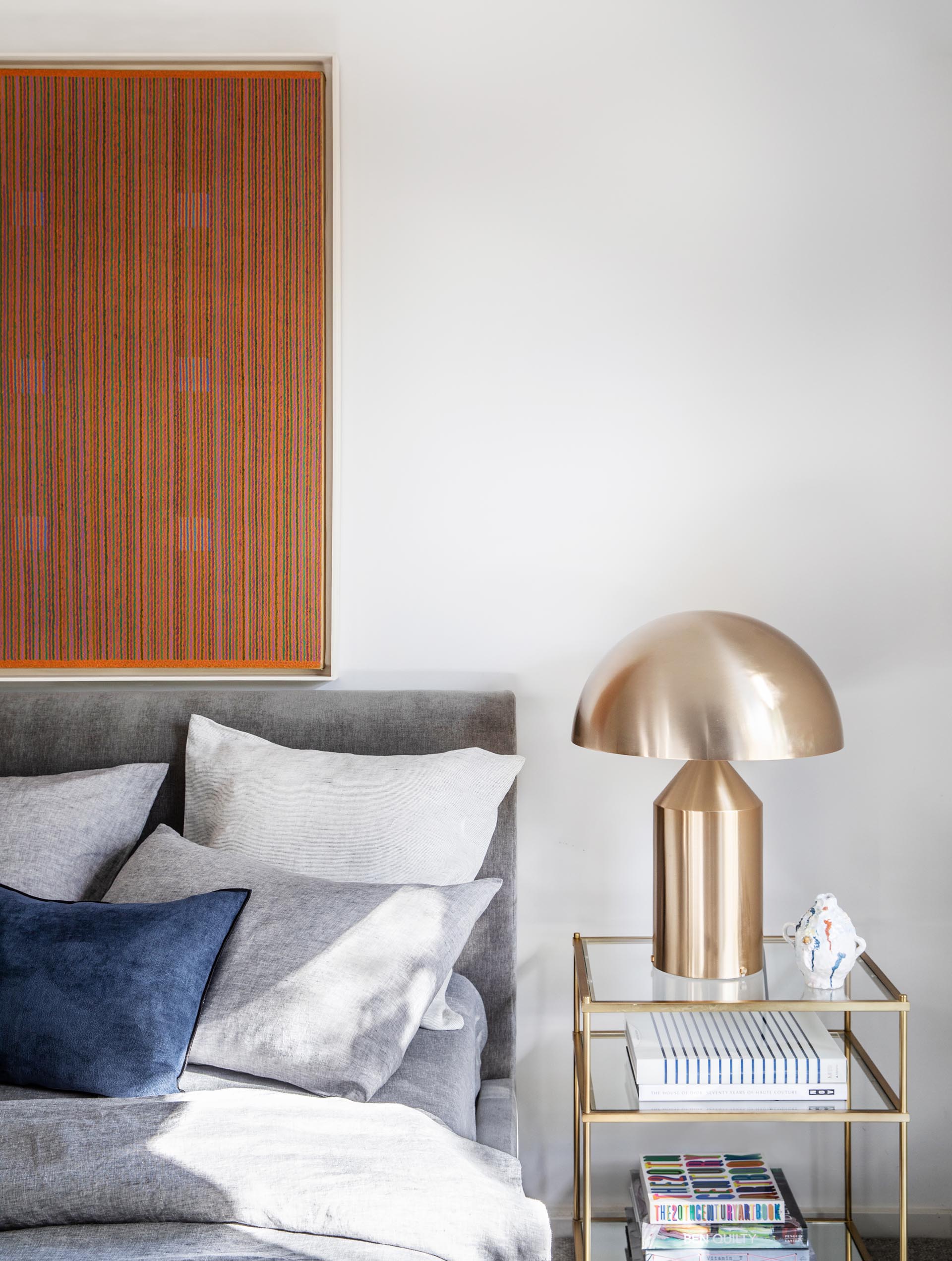 In this modern bedroom, an art piece and gray bedding adds color to the room, while the metallic accents add a touch of glamour.