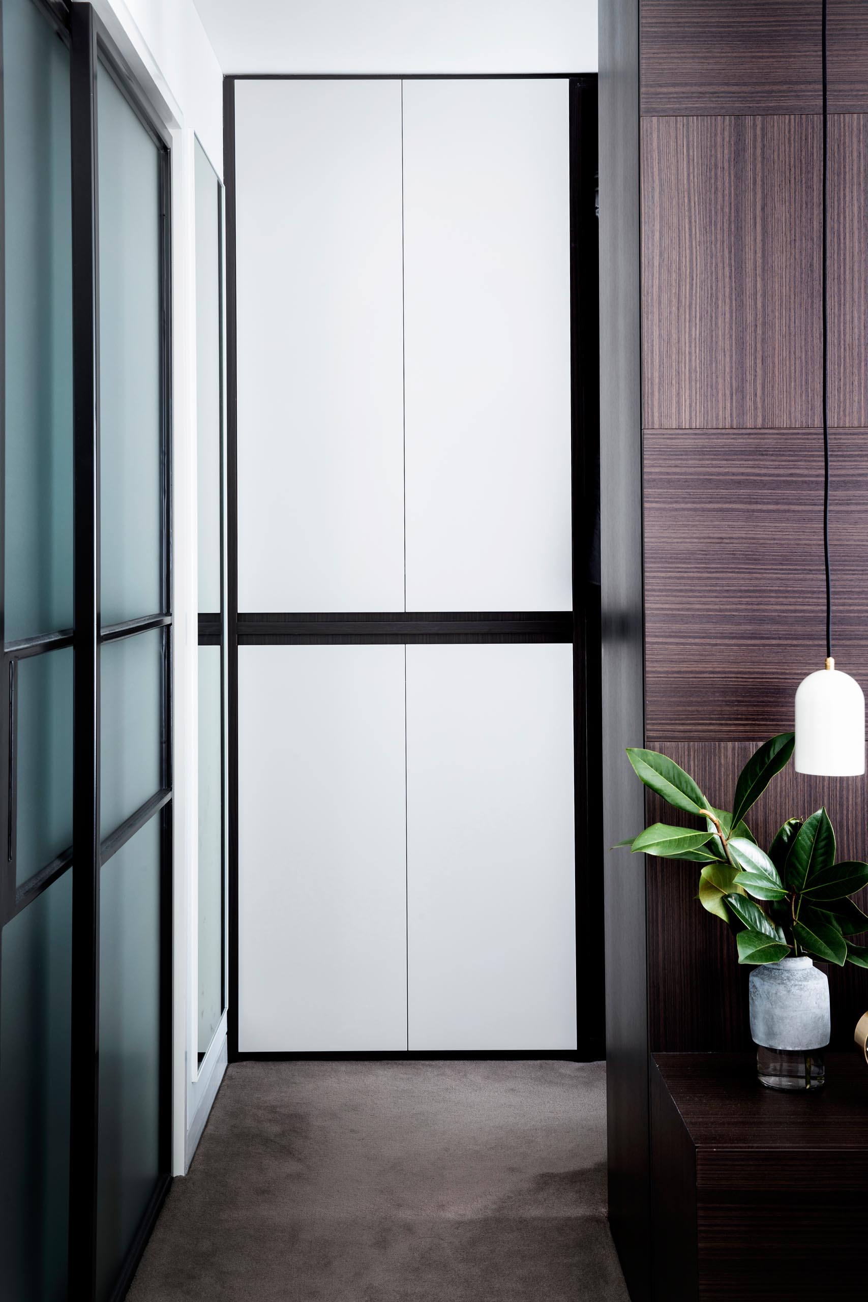 A modern master bedroom with a dark wood accent wall and a walk-through closet.