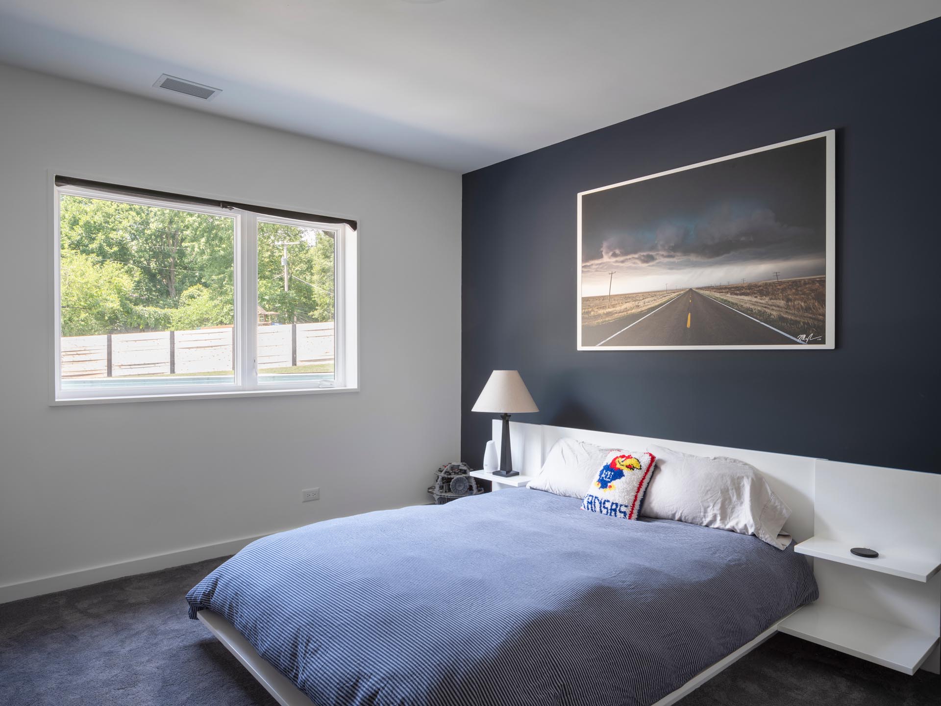 A modern bedroom with a matte black accent wall that's contrasted by a white bed frame and side tables.