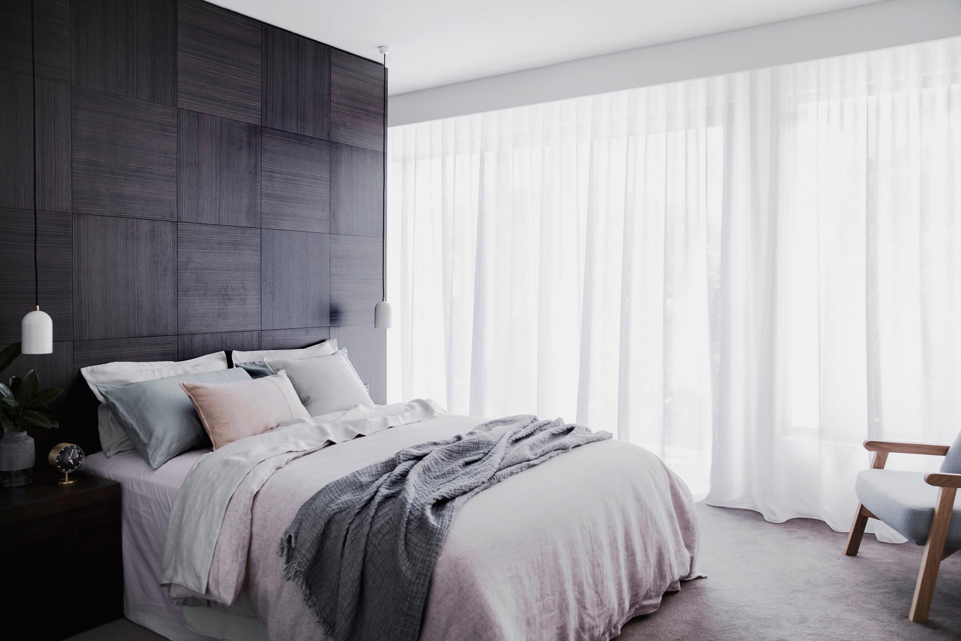 A master bedroom with a dark wood accent wall.