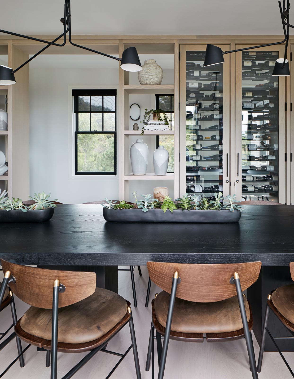 In this dining area, there's a custom designed wood shelving unit that includes glass front cabinets that show off a wine collection.