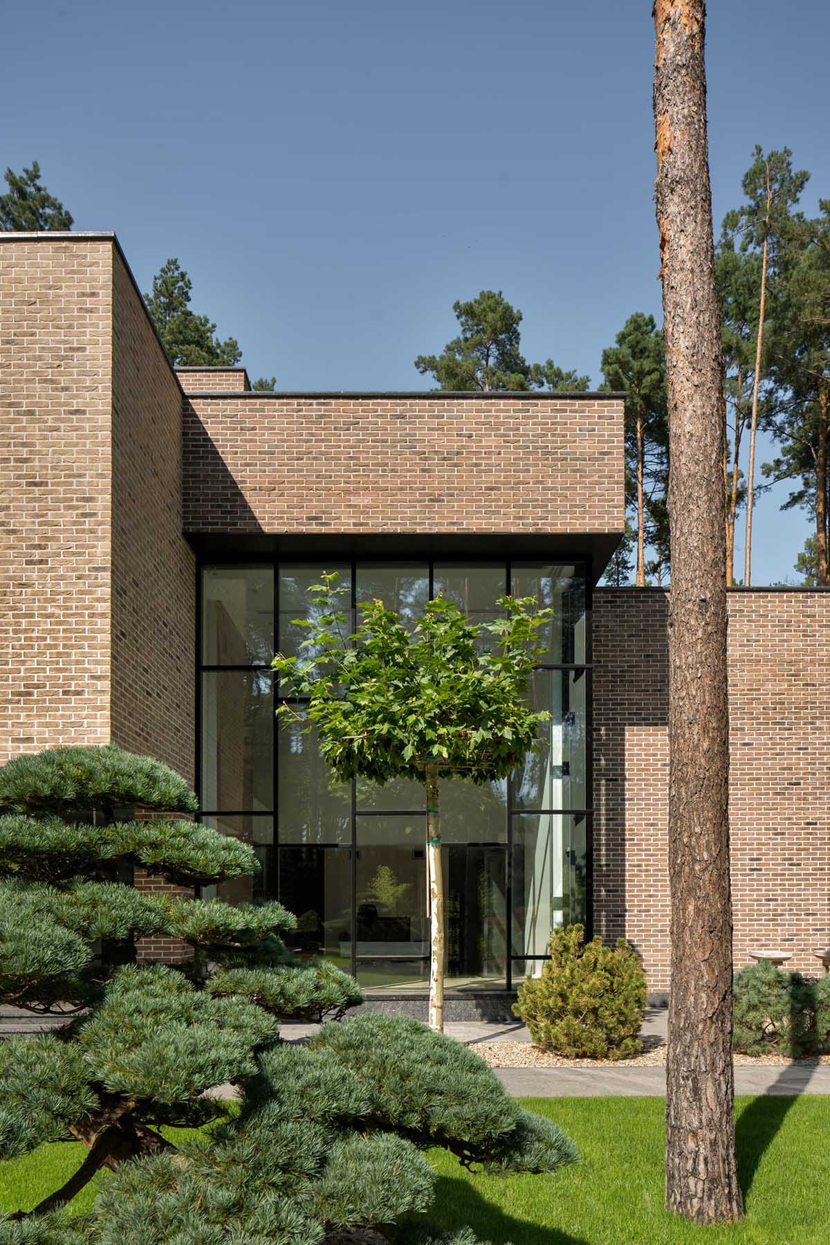 Complementing and contrasting the brown brick of this home are the black steel window frames, panels, and balcony railing.