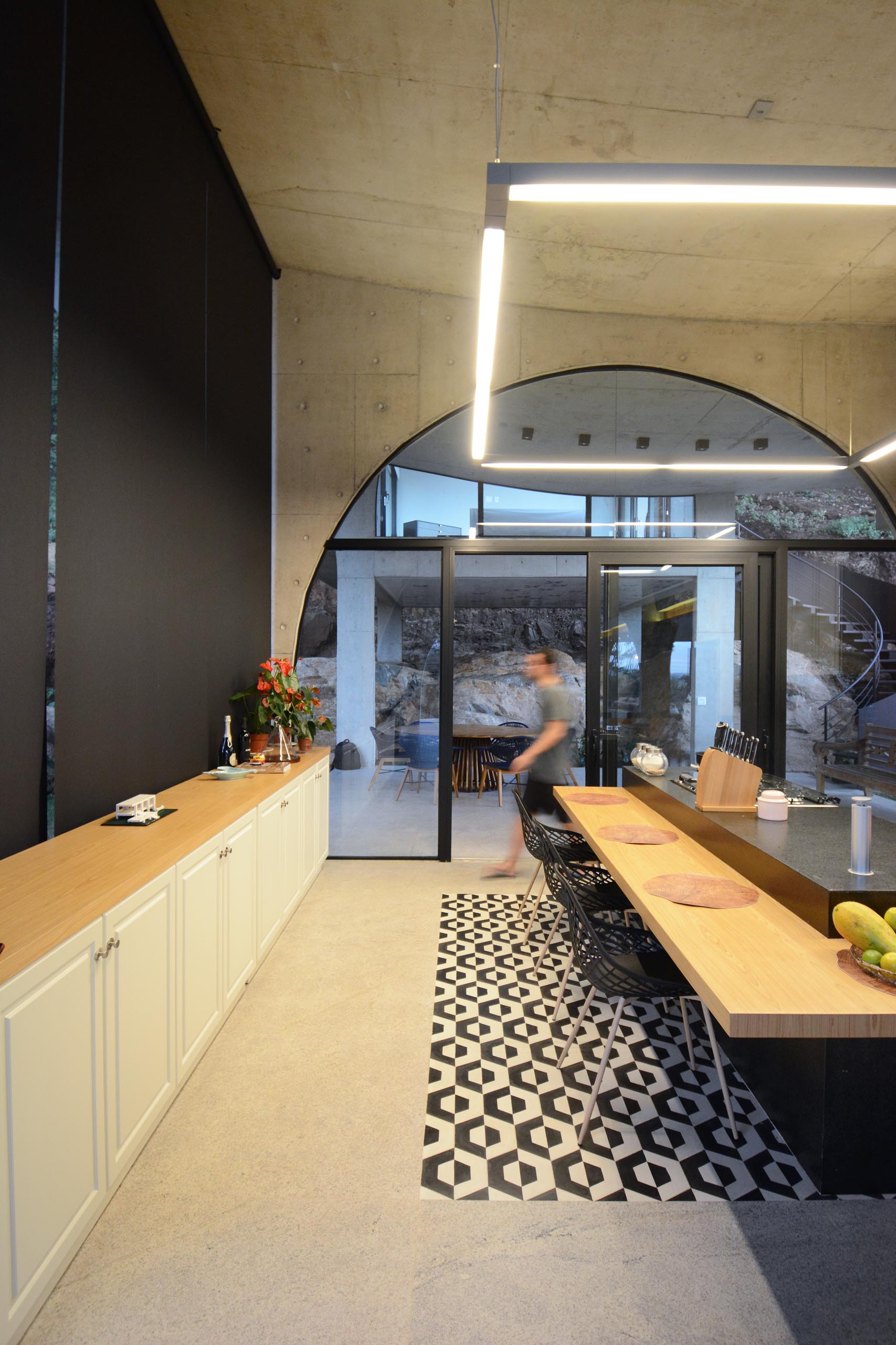 A modern kitchen with a black accent wall, and an arch with sliding glass doors that lead to a patio.