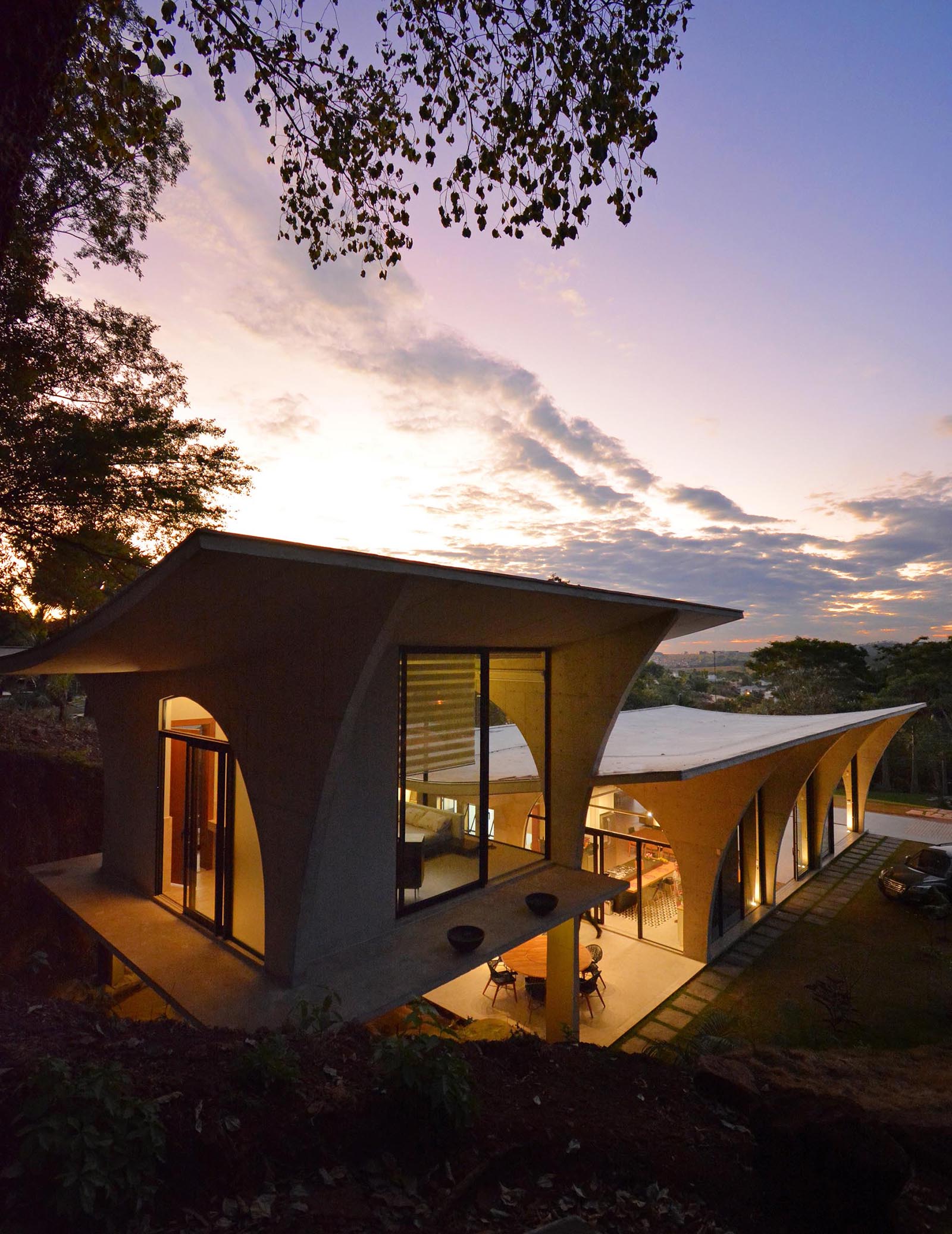 This modern concrete home features numerous arches, which are especially visible at night as the interior light highlights the curves.