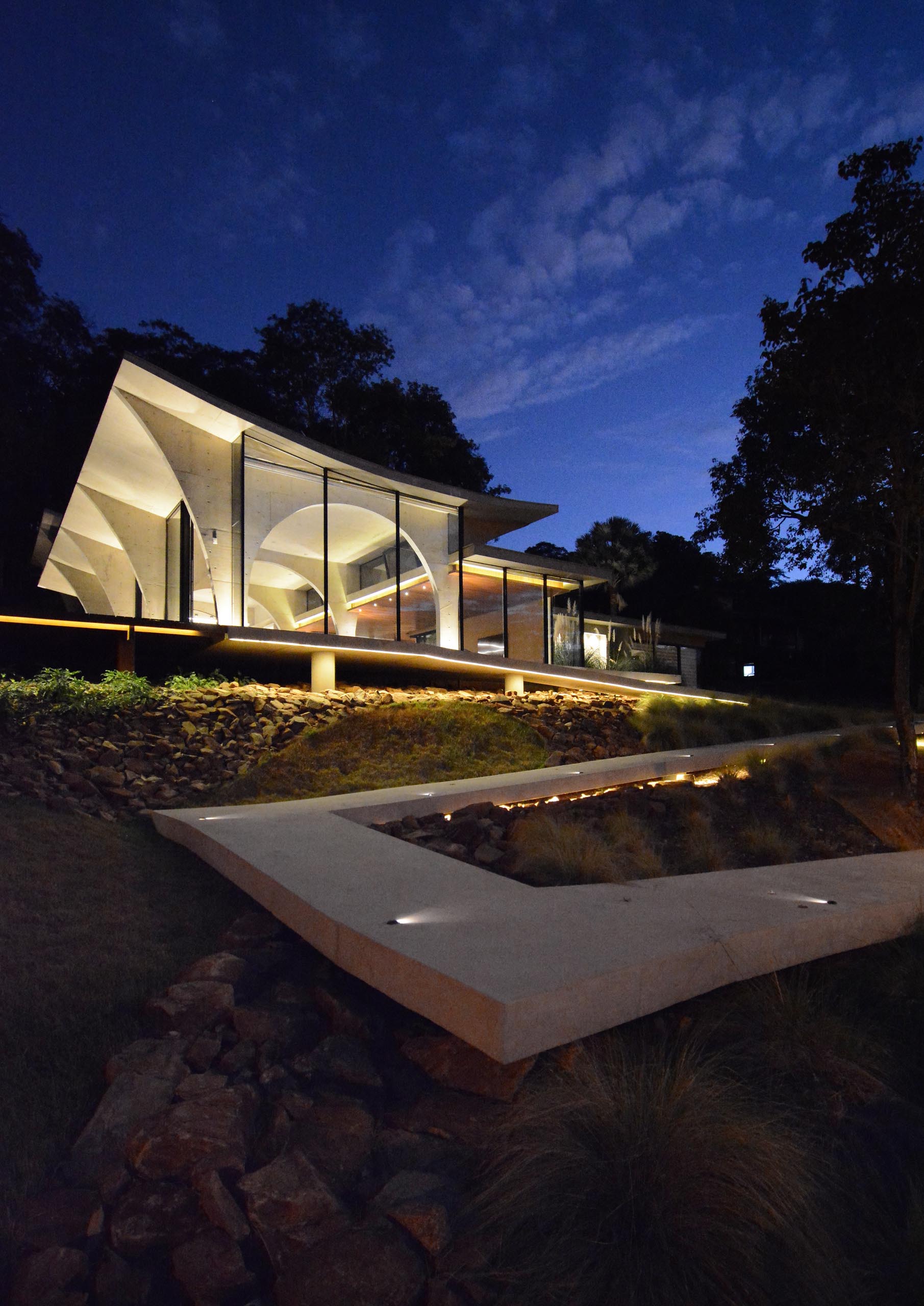 This modern concrete home features numerous arches, which are especially visible at night as the interior light highlights the curves.